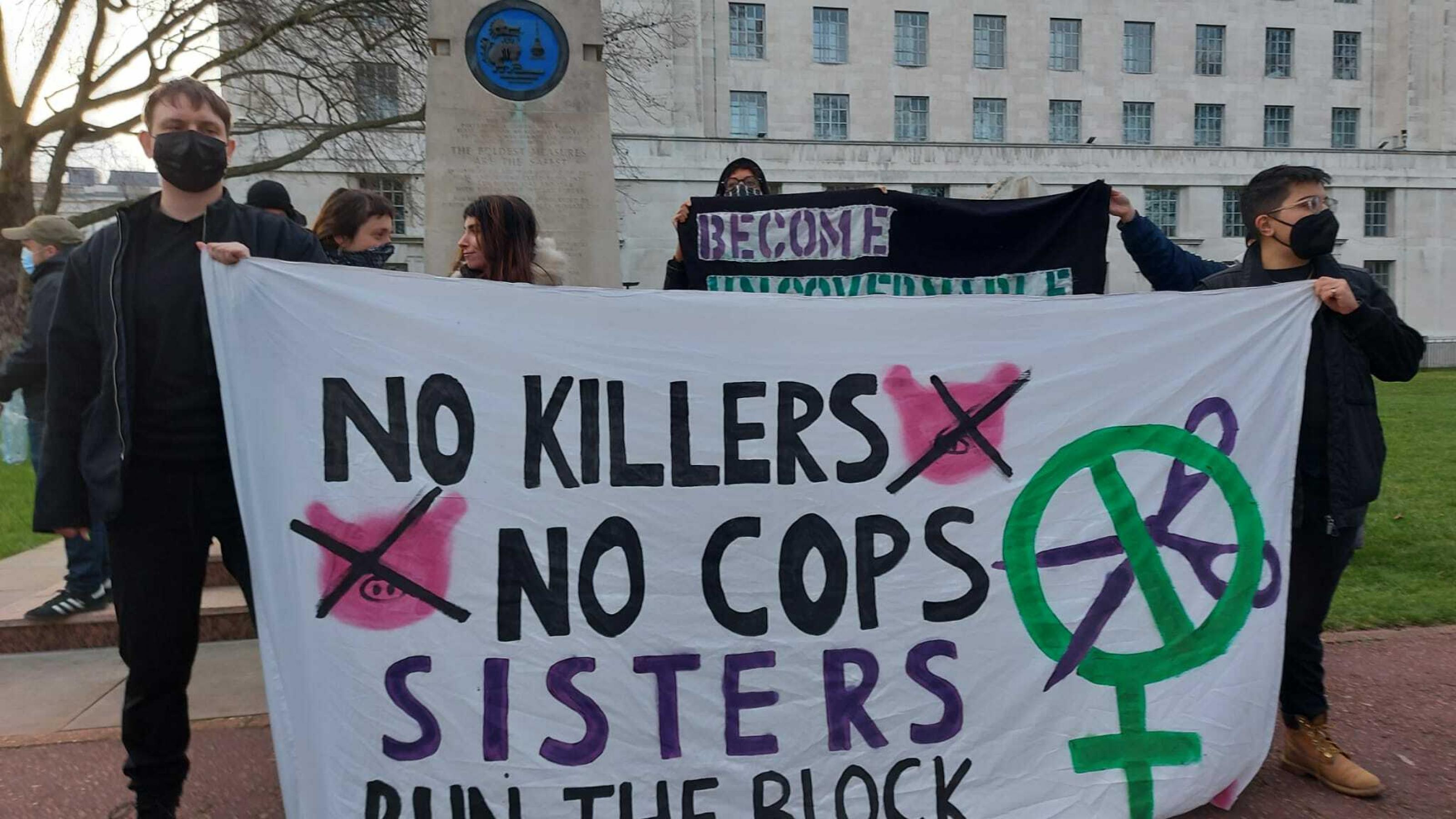 Protestierende halten ein Spruchband, auf dem steht: „No Killers, no cops, Sisters run the block“