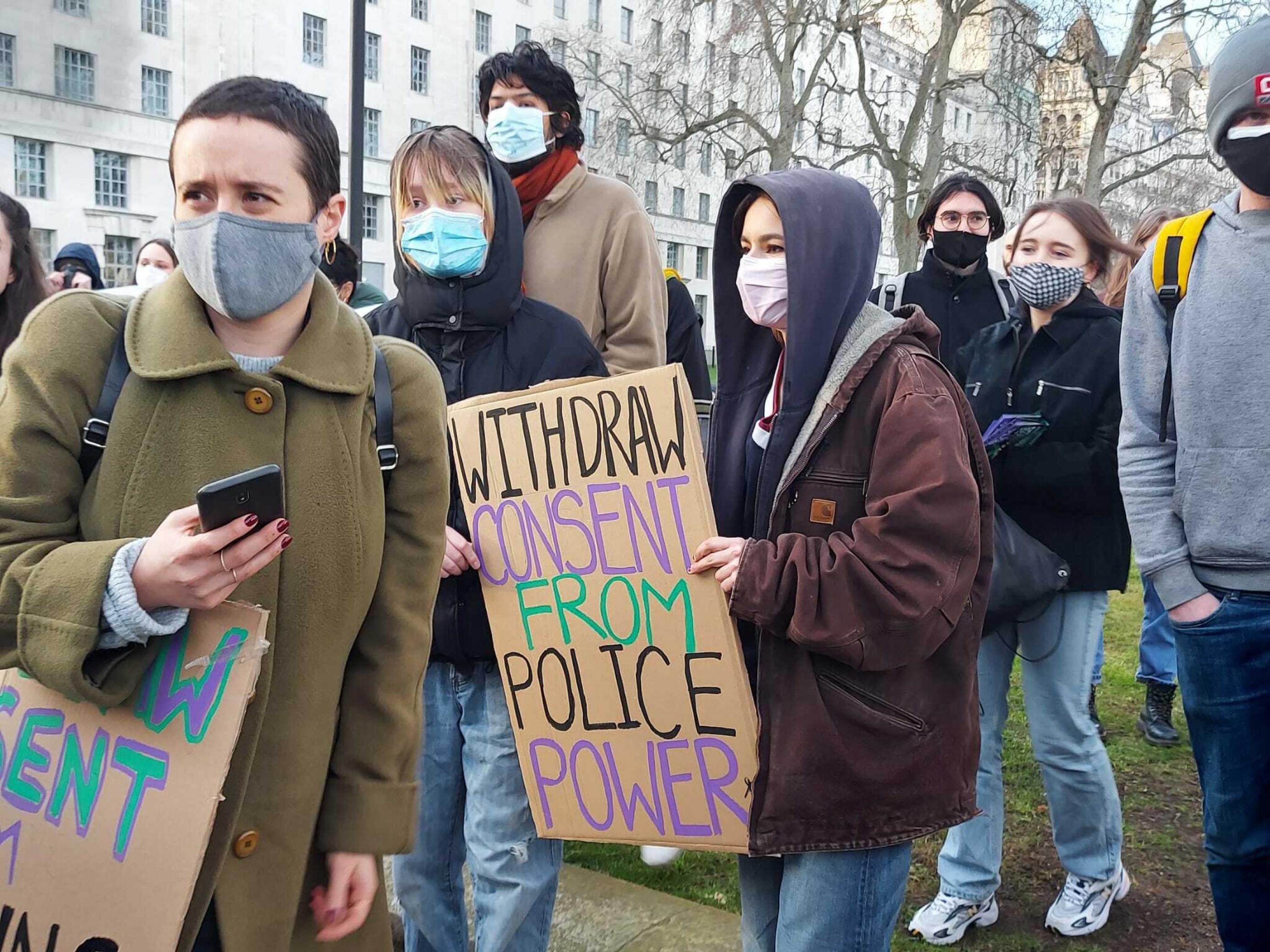 Protestierende hält ein Schild hoch, auf dem steht: Withdraw Consent from Police power.