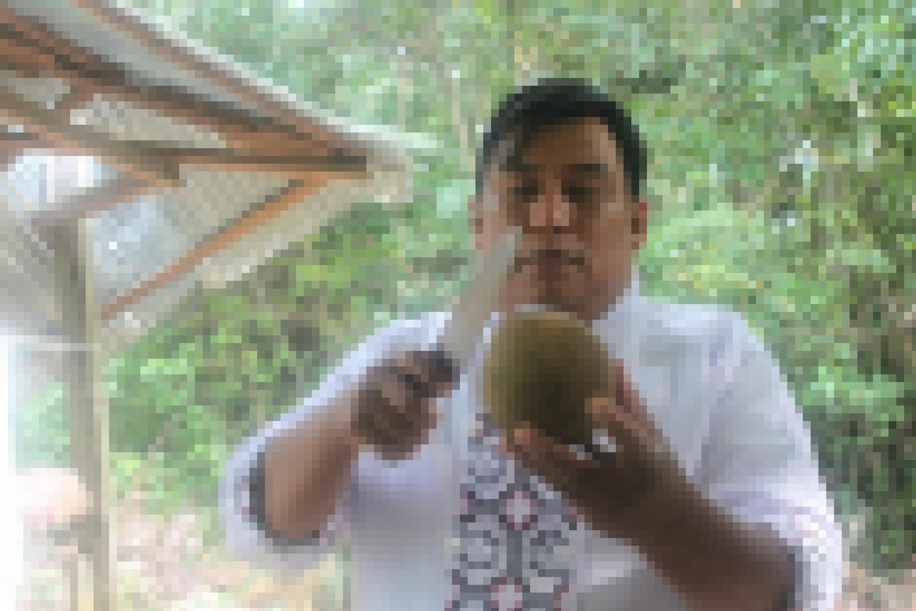 Mann mit Messer und runder Kokosnuss-großer Frucht in der Hand.