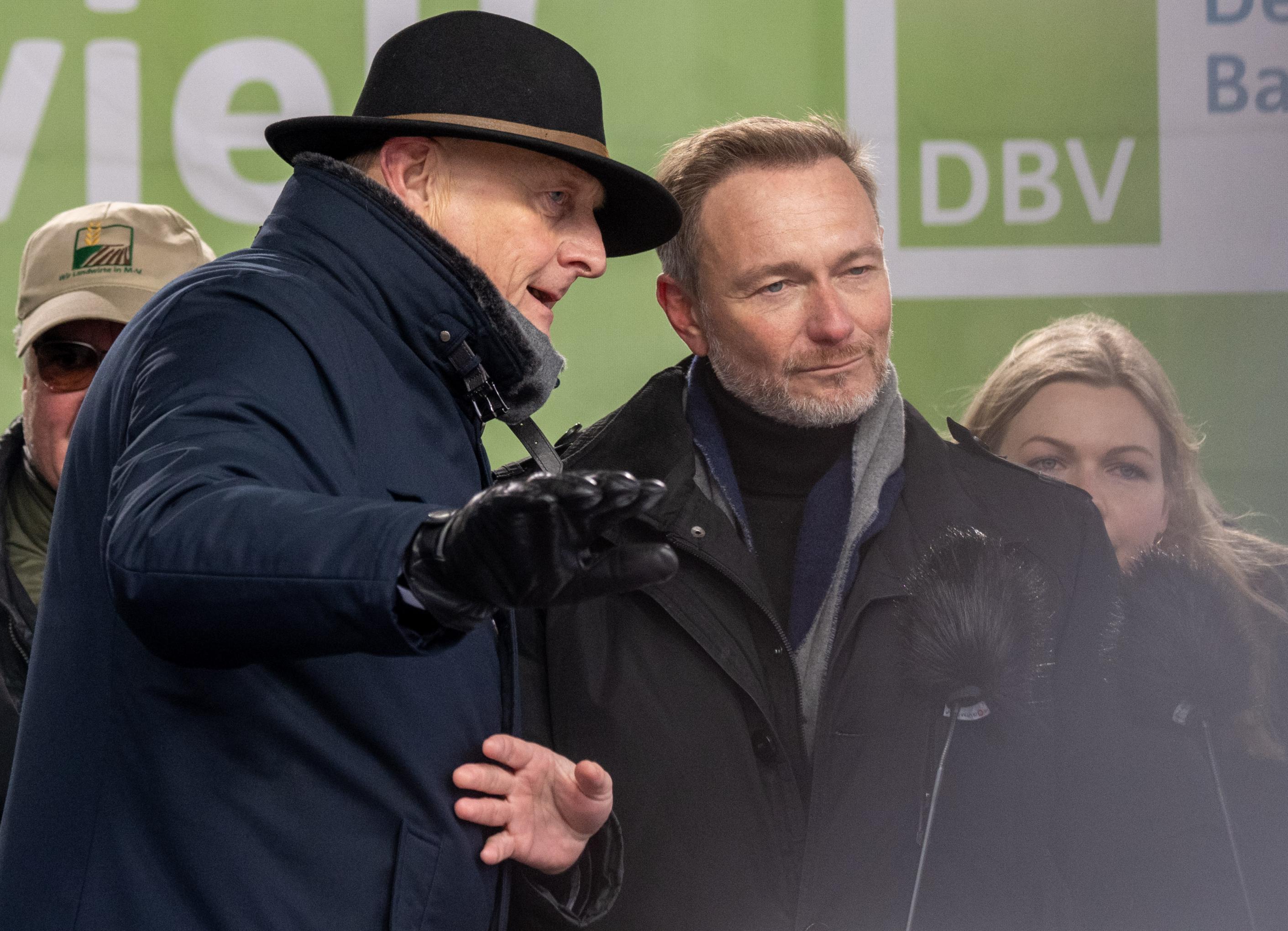 Halbnahe Aufnahme von Christian Lindner (rechts, FDP), Bundesminister für Finanzen, und Joachim Rukwied, Präsident des Deutschen Bauernverbandes. Sie tragen Winterjacken. Ruckwied trägt einen schwarzen Hut und schwarze Lederhandschuhe. Lindner neigt seinen Kopf leicht zu Rukwied - scheinbar sind diese im Gespräch.