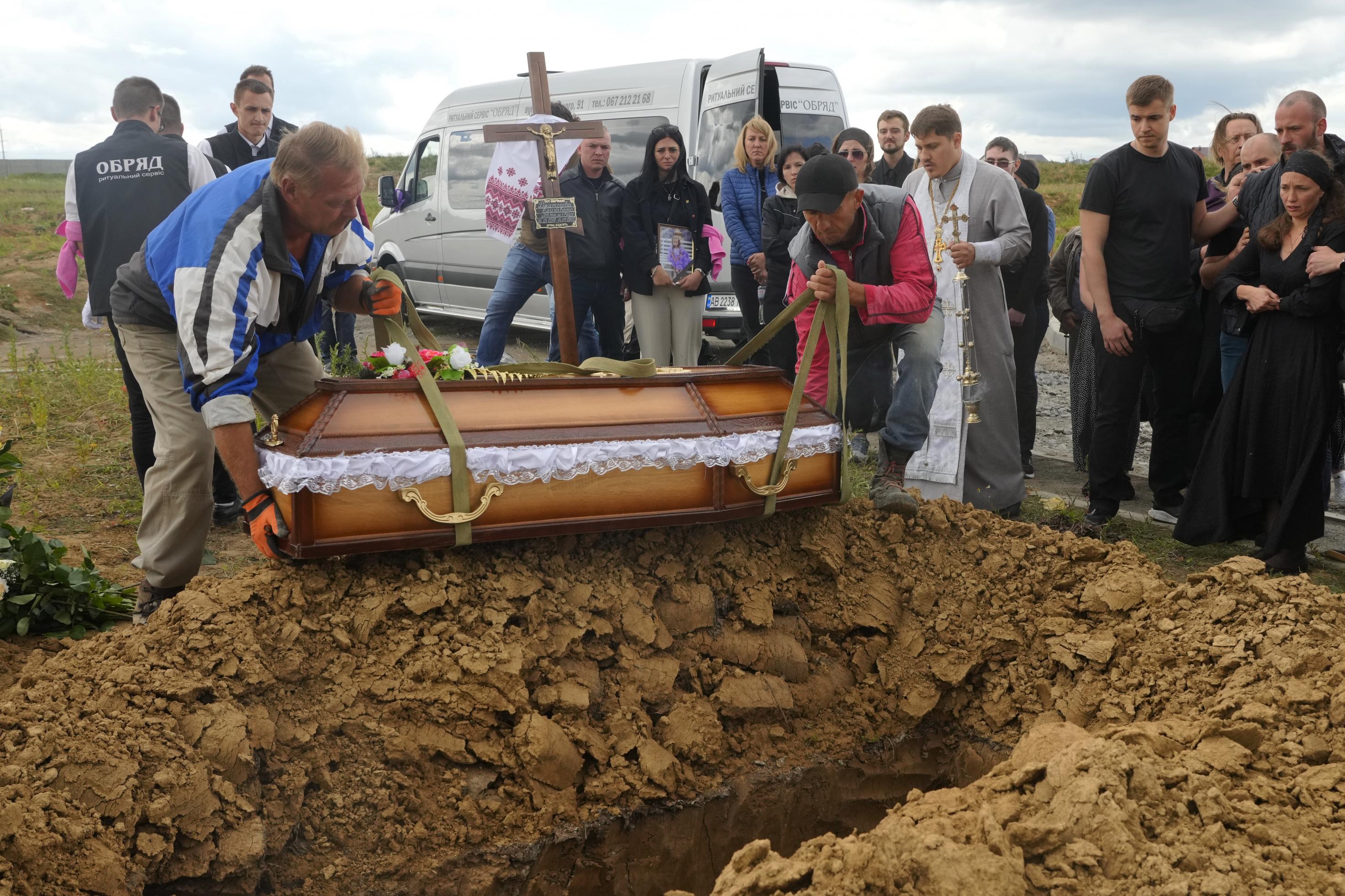 Men lower the coffin of Liza, 4-year-old girl killed by Russian attack, during a funeral ceremony in Vinnytsia, Ukraine, Sunday, July 17, 2022. Wearing a blue denim jacket with flowers, Liza was among 23 people killed, including two boys aged 7 and 8, in Thursday's missile strike in Vinnytsia. Her mother, Iryna Dmytrieva, was among the scores injured. (AP Photo/Efrem Lukatsky)