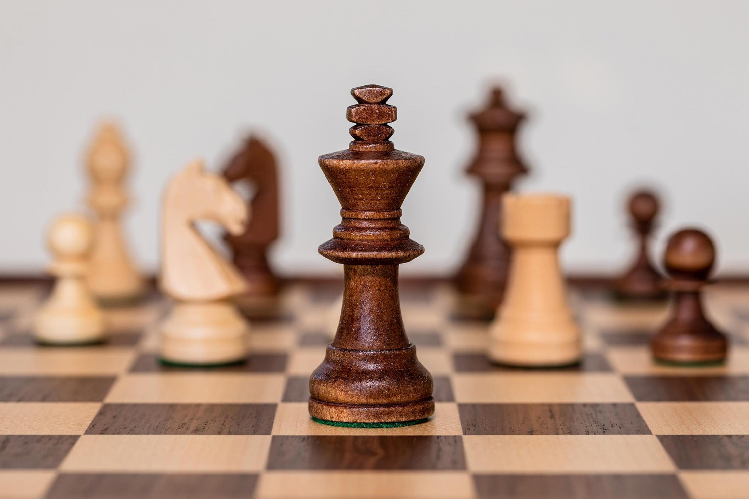 Blick auf eine Schachbrett aus Holz mit Holzfiguren, der Fokus liegt auf dem König von Schwarz