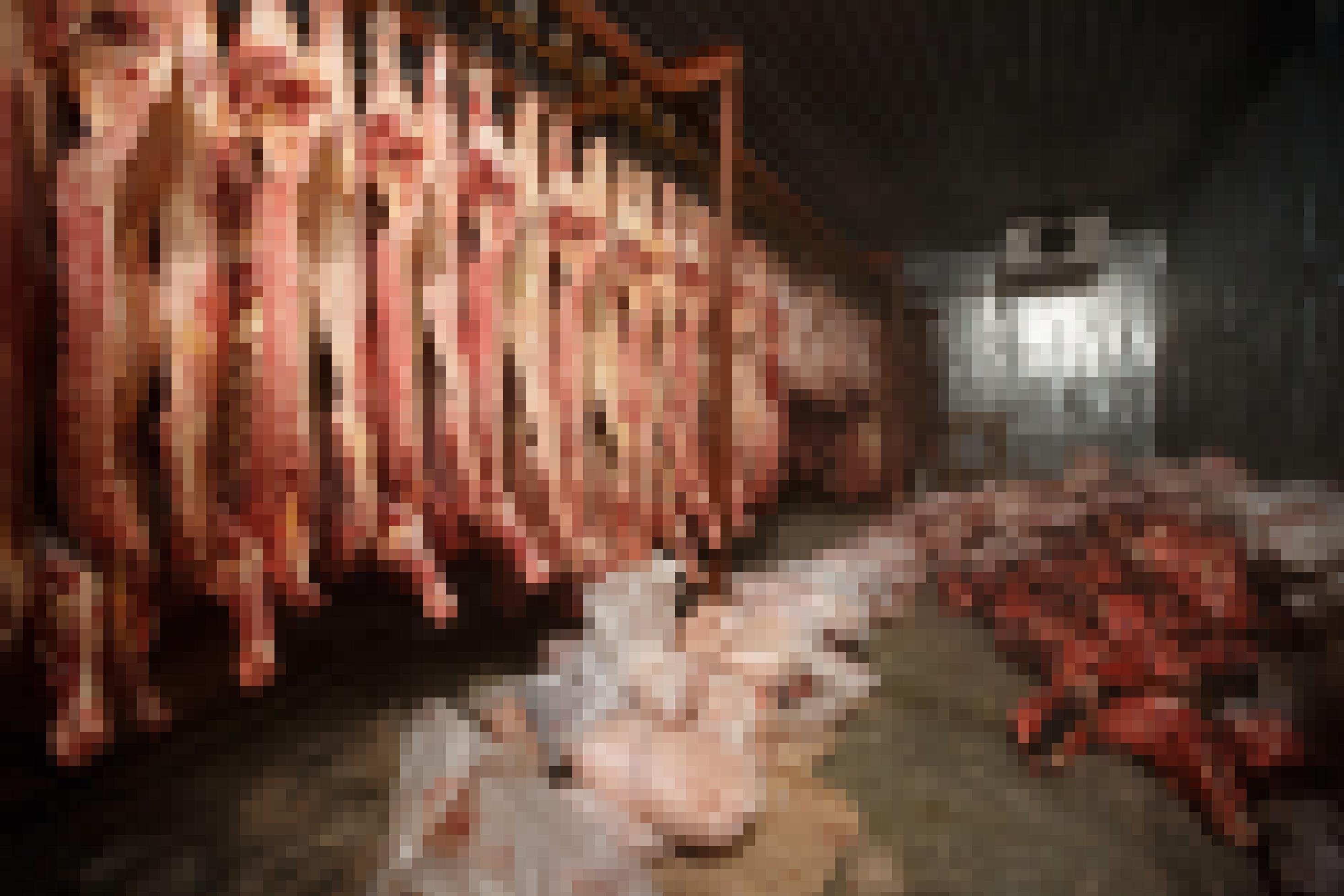 Eine Totale zeigt ein Schlachthaus. Links hängen Rinderhälften, am Boden liegen weitere Fleischteile.