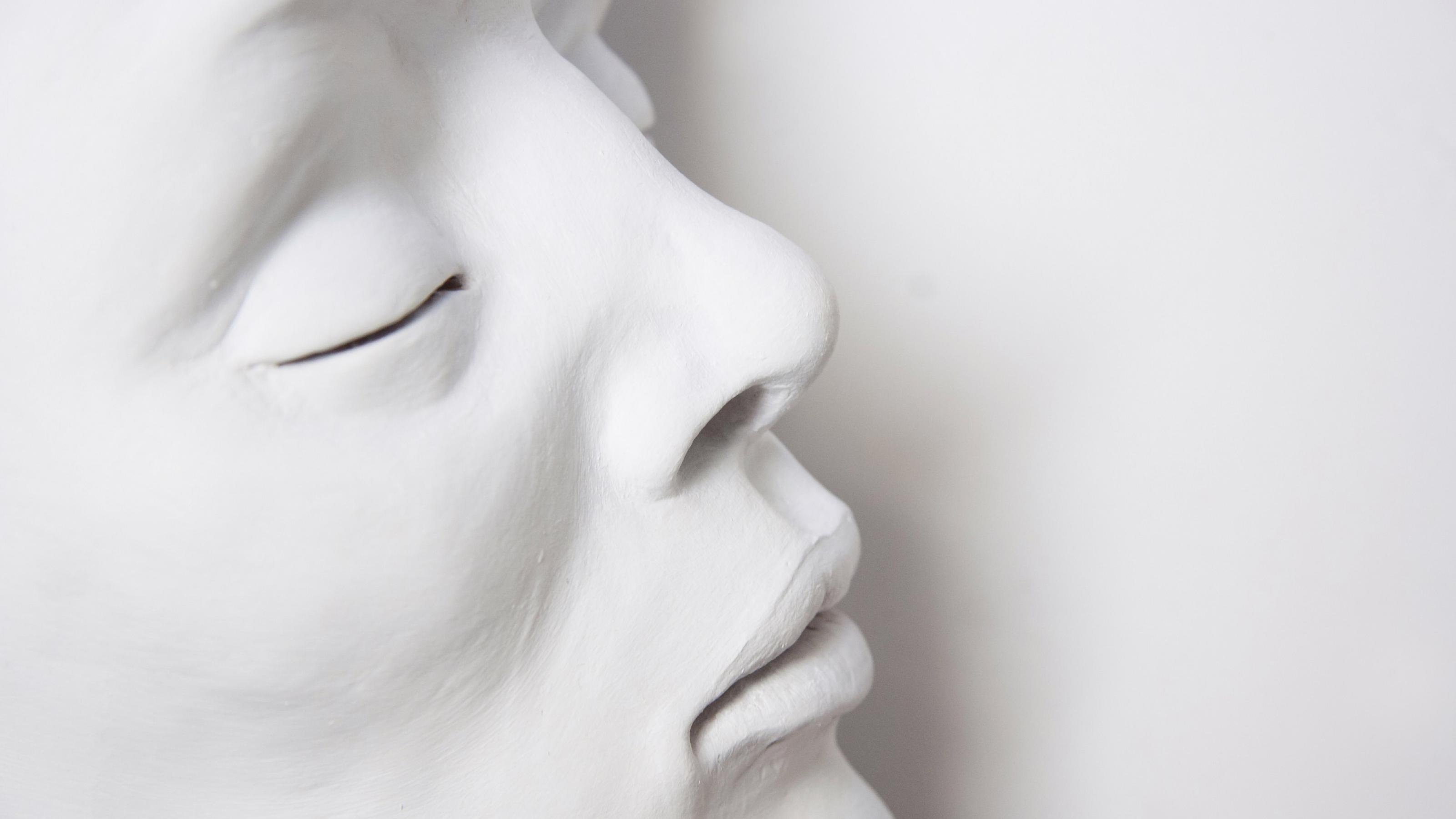 Komplett weiß geschminktes Gesicht einer schlafenden Frau mit geschlossenen Augenlidern