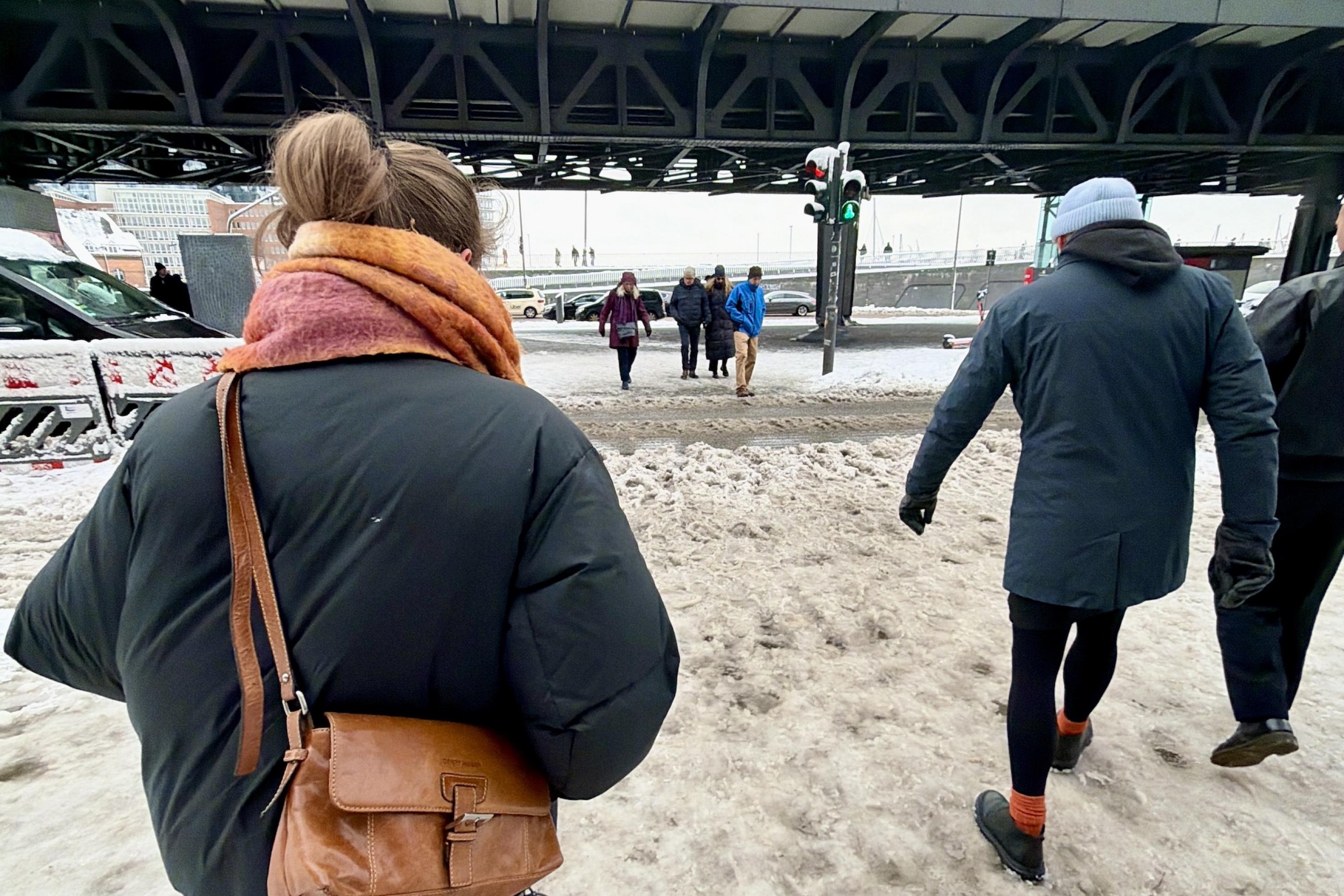 Männer und Frauen gehen über verschneite Gehwege.