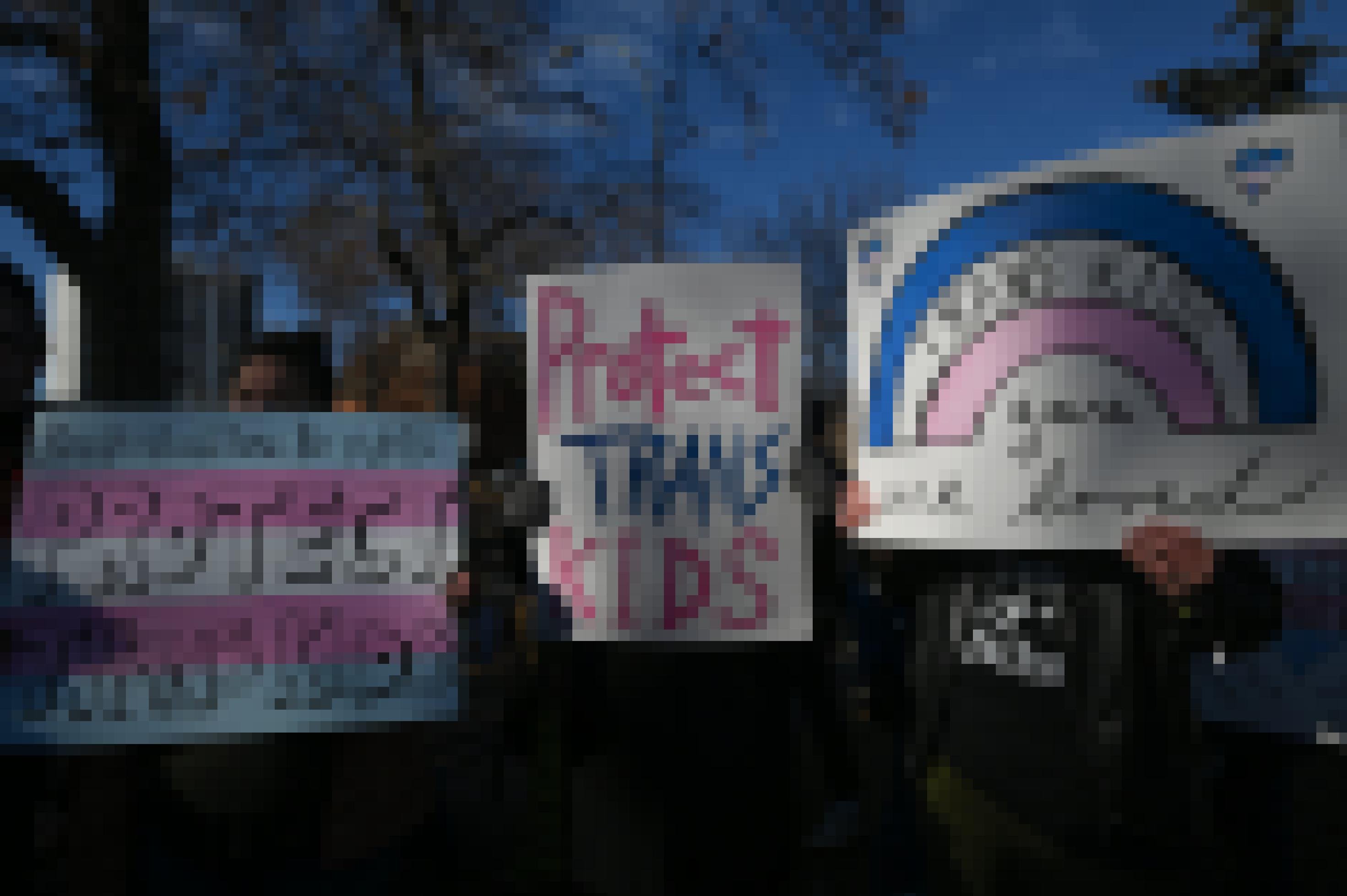 Drei Personen halten bei einer Demonstration Plakate in die Höhe. Darauf steht: „Trans kids, you are loved“ und „Protect trans Kids“.