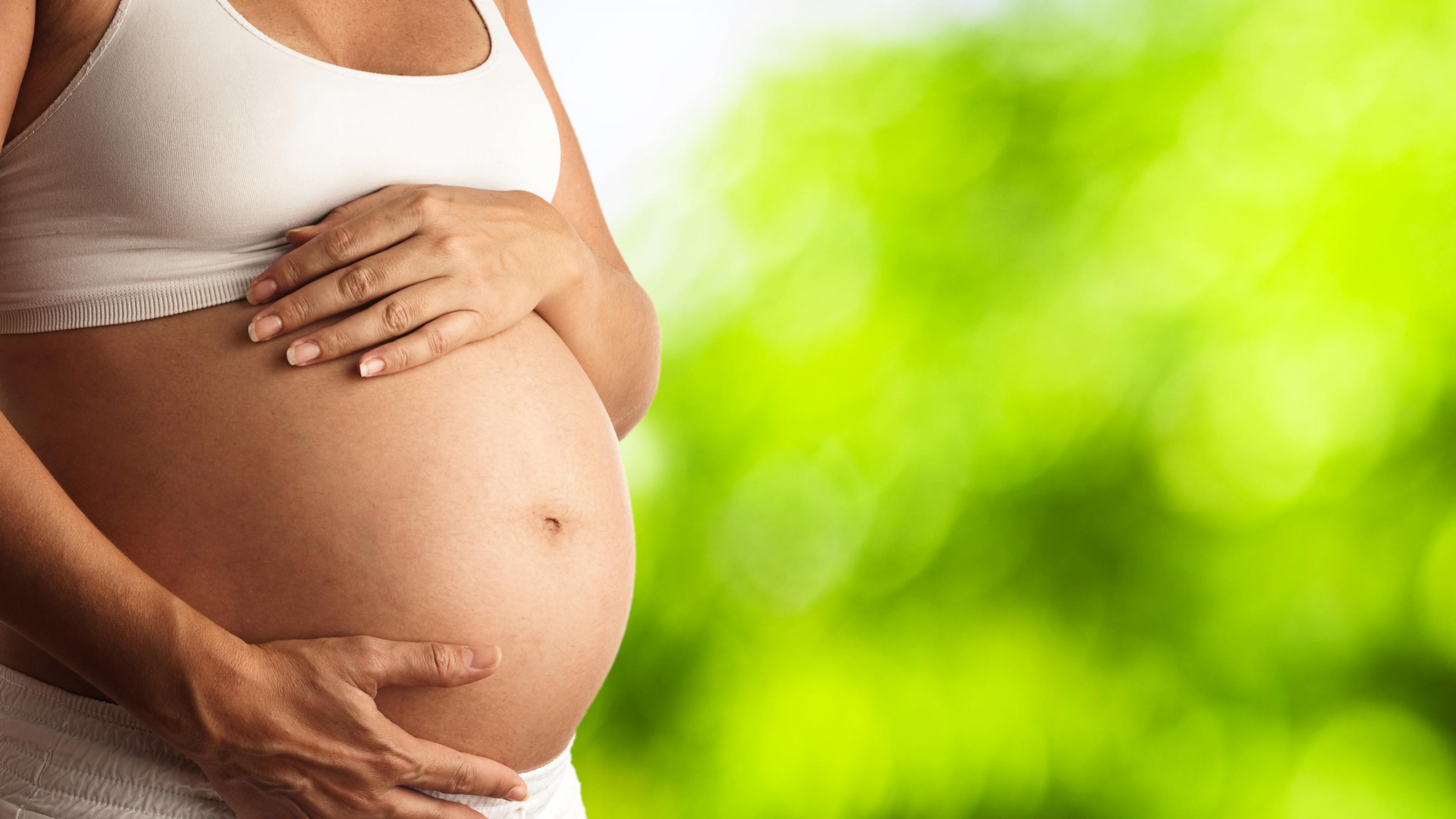 Schwangere hält ihre Hände an ihren Babybauch. Hitzewarnungen und Handlungsempfehlungen werden noch zu selten an Schwangere kommuniziert.