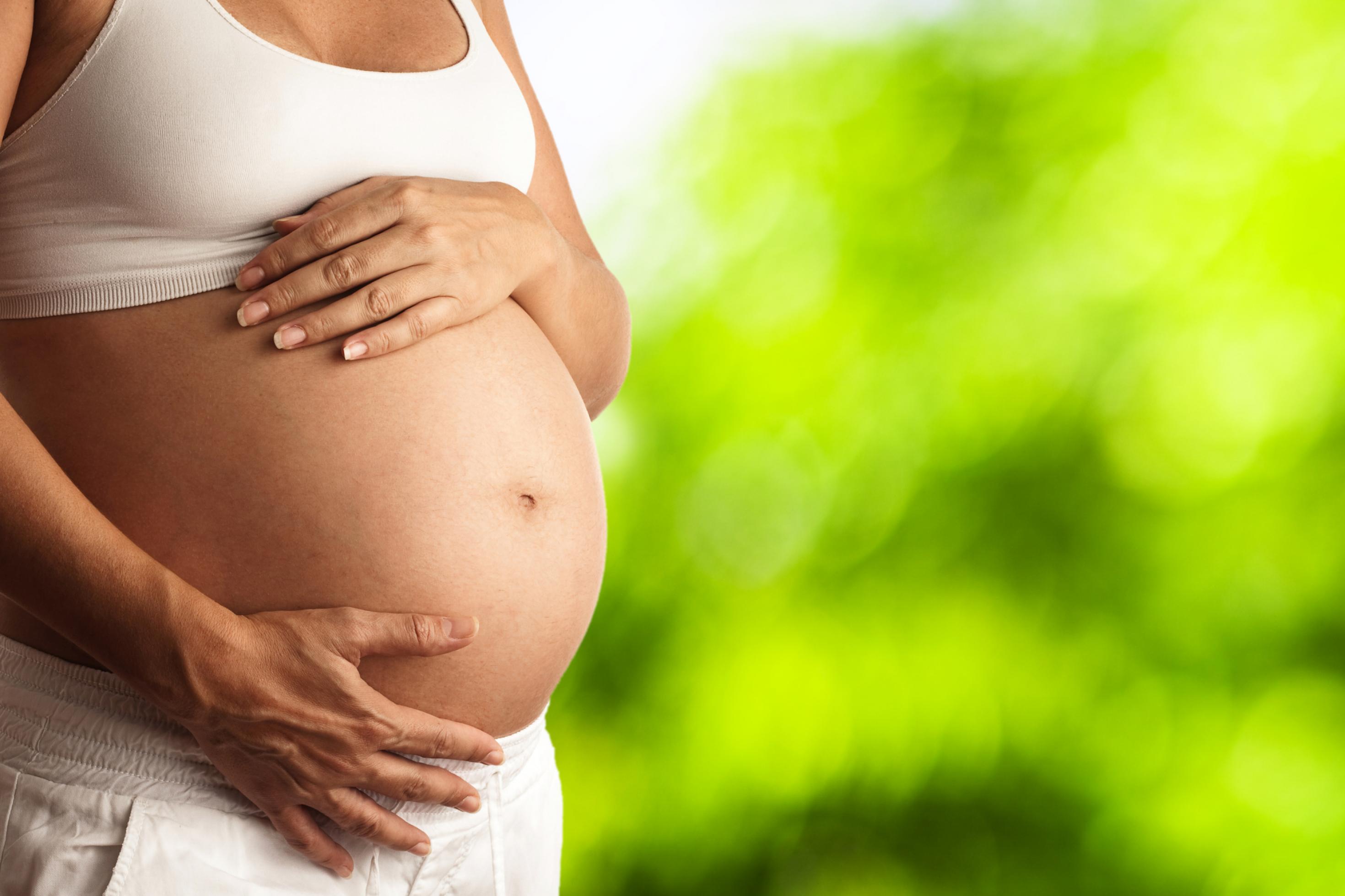 Schwangere hält ihre Hände an ihren Babybauch. Hitzewarnungen und Handlungsempfehlungen werden noch zu selten an Schwangere kommuniziert.