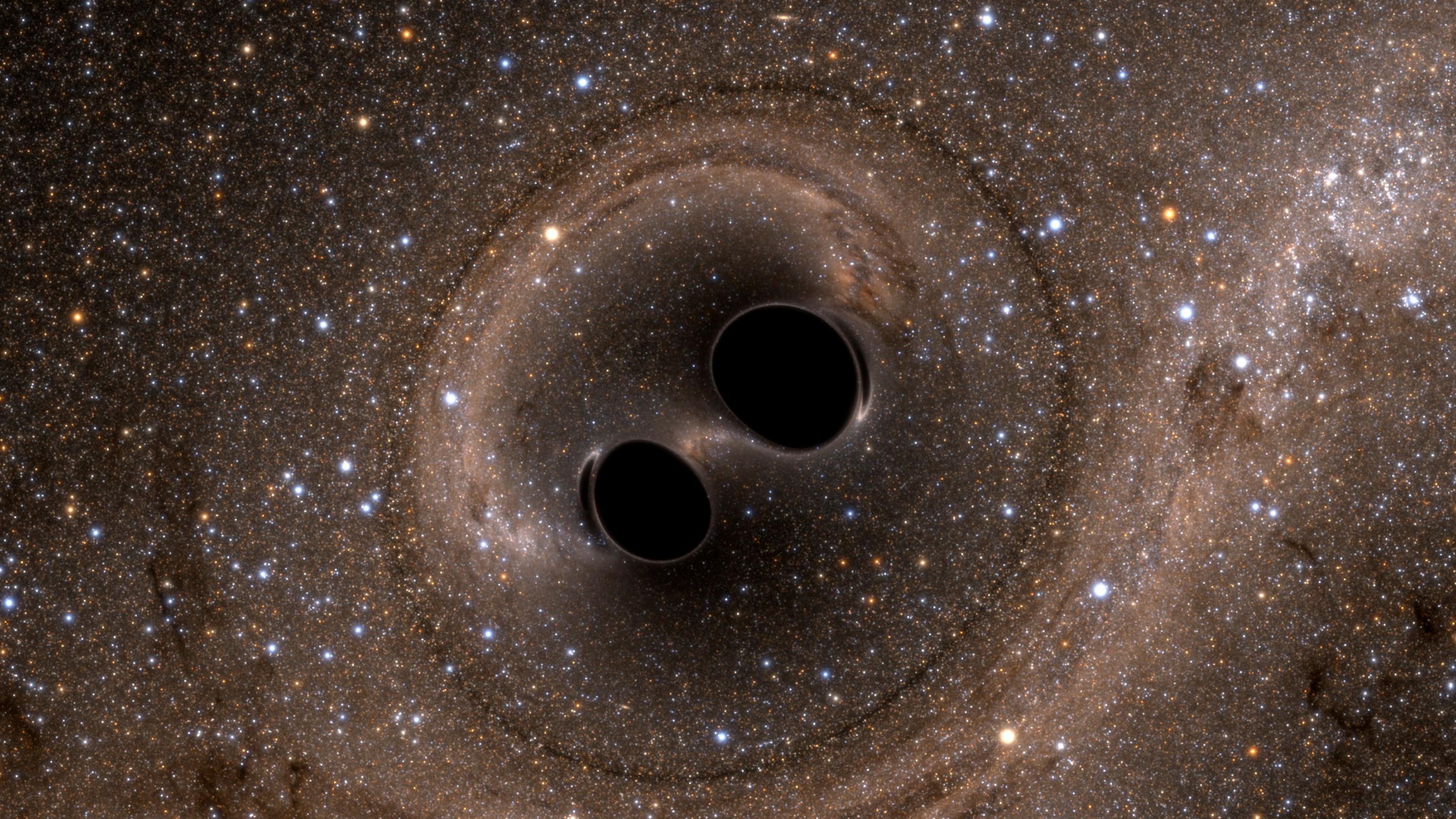 Zwei Schwarze Löcher, die wirklich schwarz und nah beieinander sind. Der Sternenhintergrund um sie herum wirkt verquirlt.