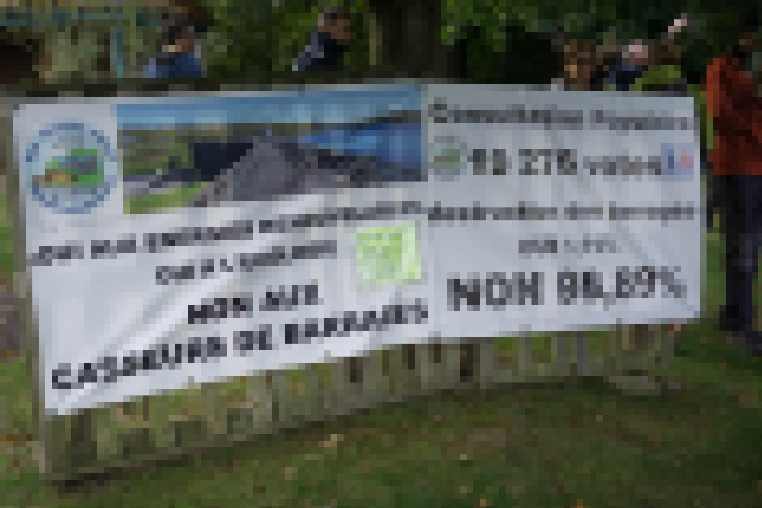 Ein Transparent mit der Aufschrift „Non 98,89 %“ hängt an einem Zaun.
