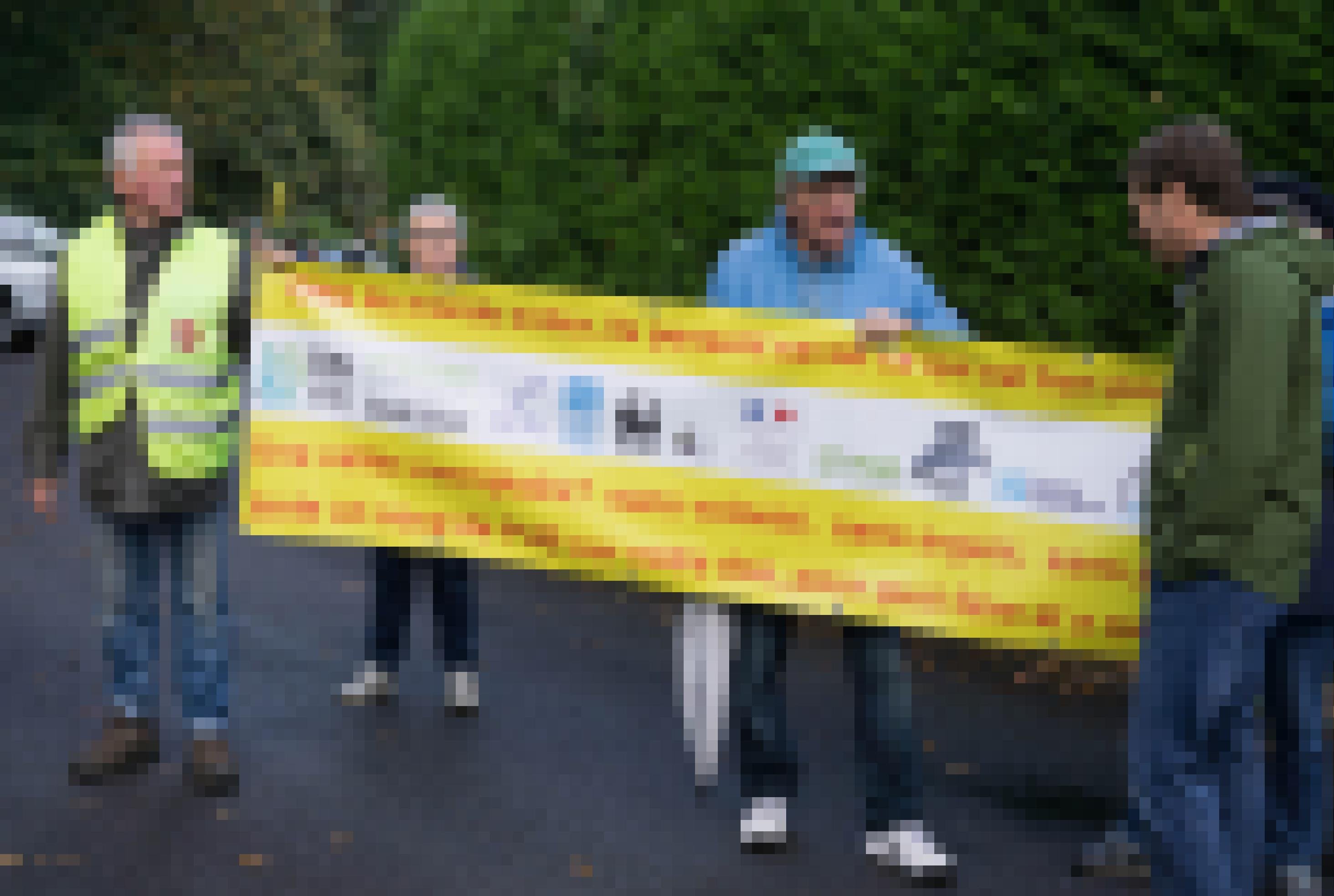 Vier Männer demonstrieren mit einem Transparent.