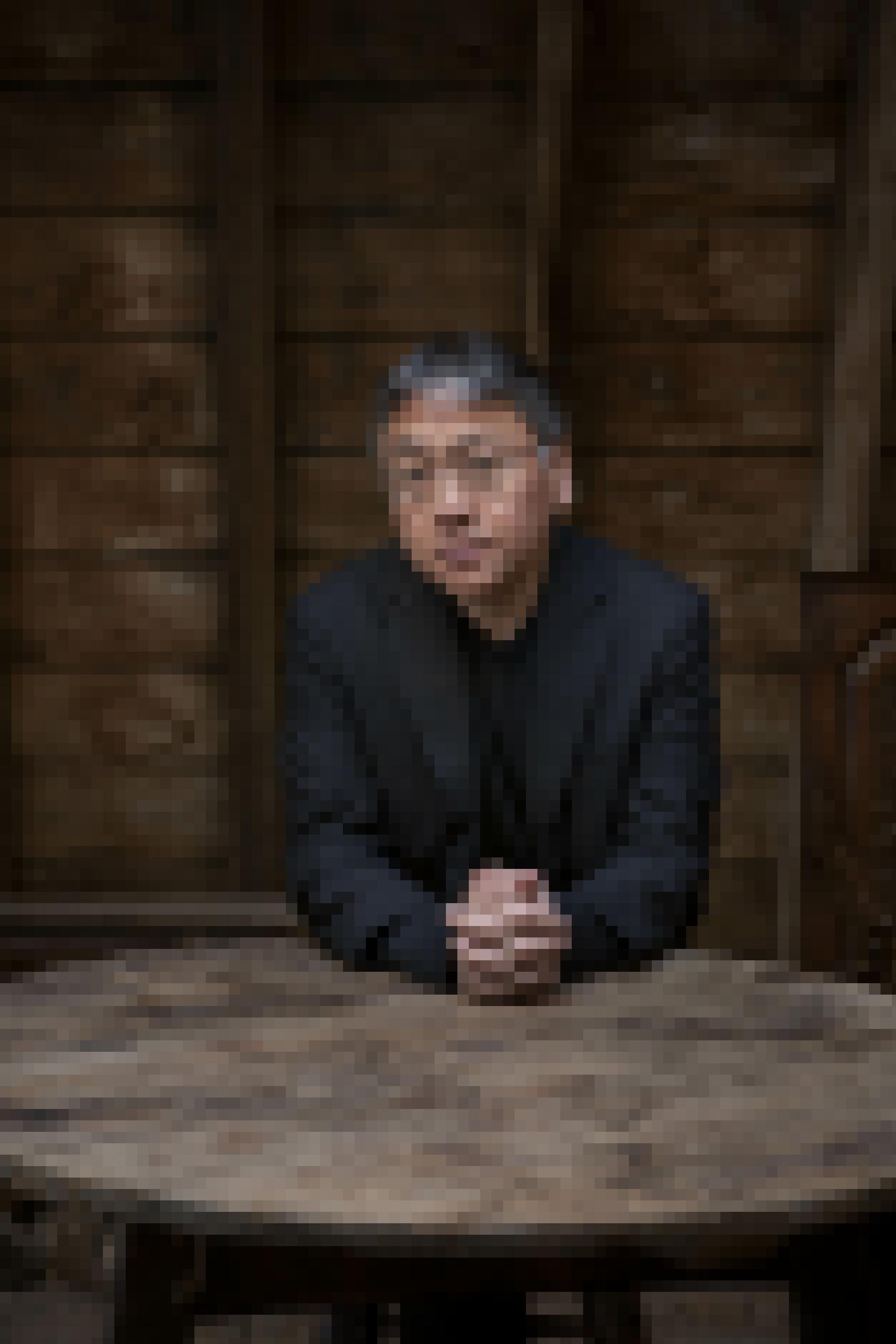 Nobelpreisträger Kazuo Ishiguro sitzt mit verschränkten Händen an einem Tisch.