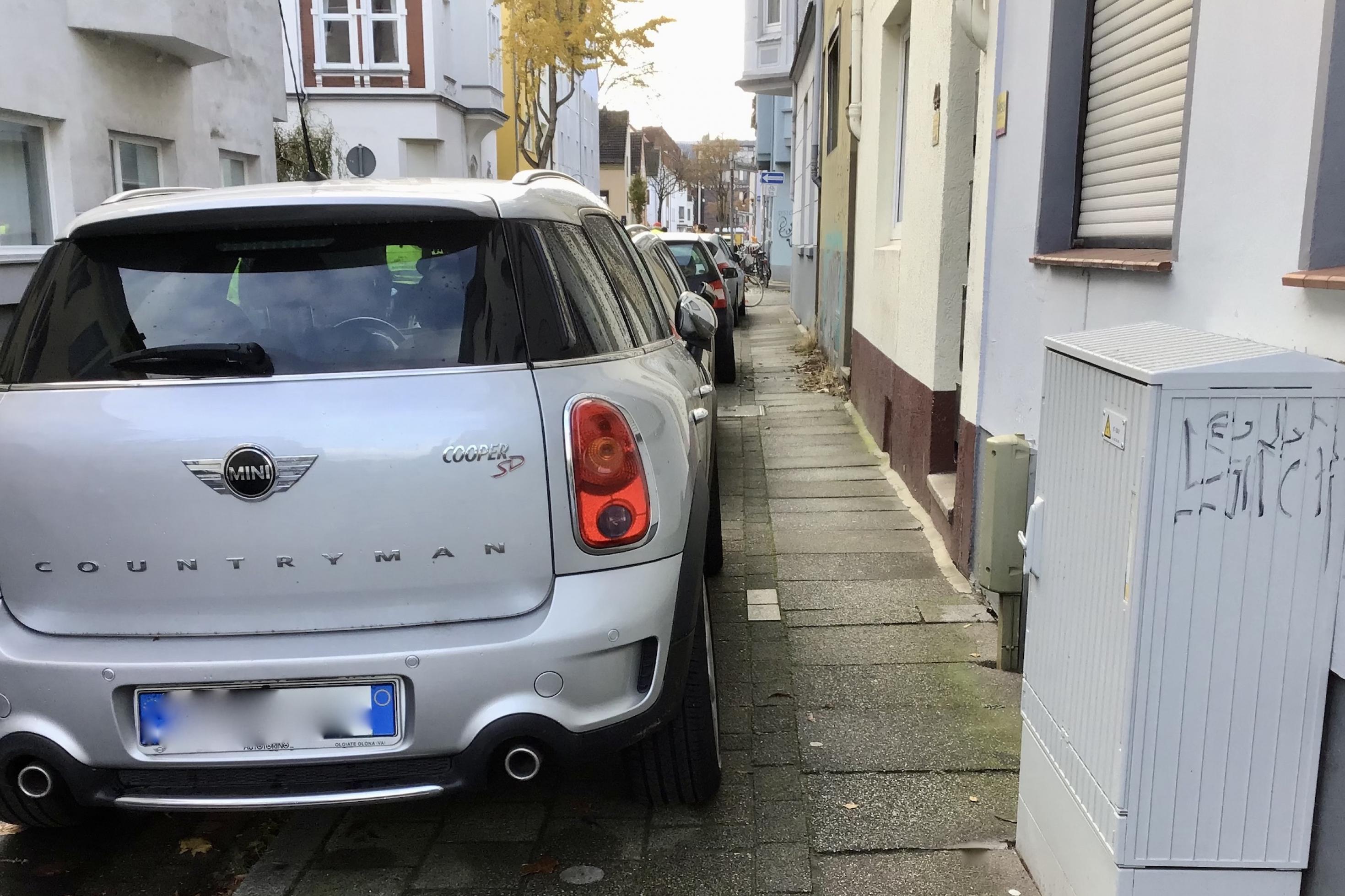 Ein Auto steht mit zwei Reifen auf dem Gehweg