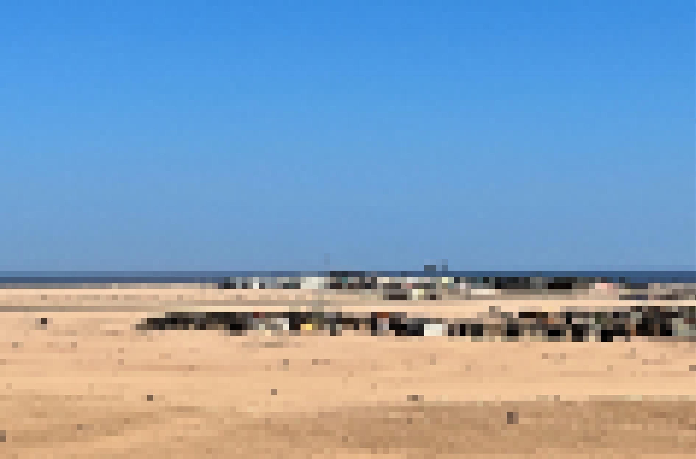 Kleine Häuschen stehen in einer trostlosen Wüstenlandschaft an der Küste