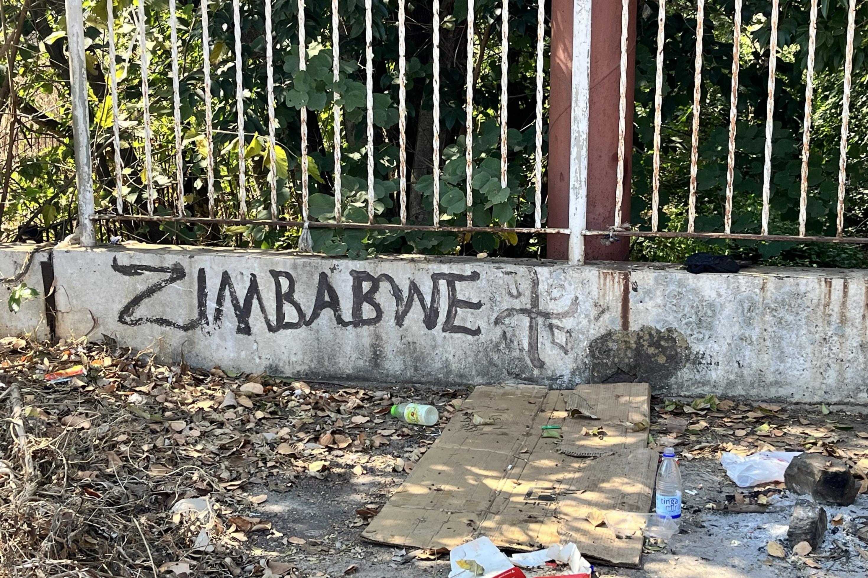 Auf eine Mauer hat jemand Zimbabwe geschrieben. Davor liegt Müll.