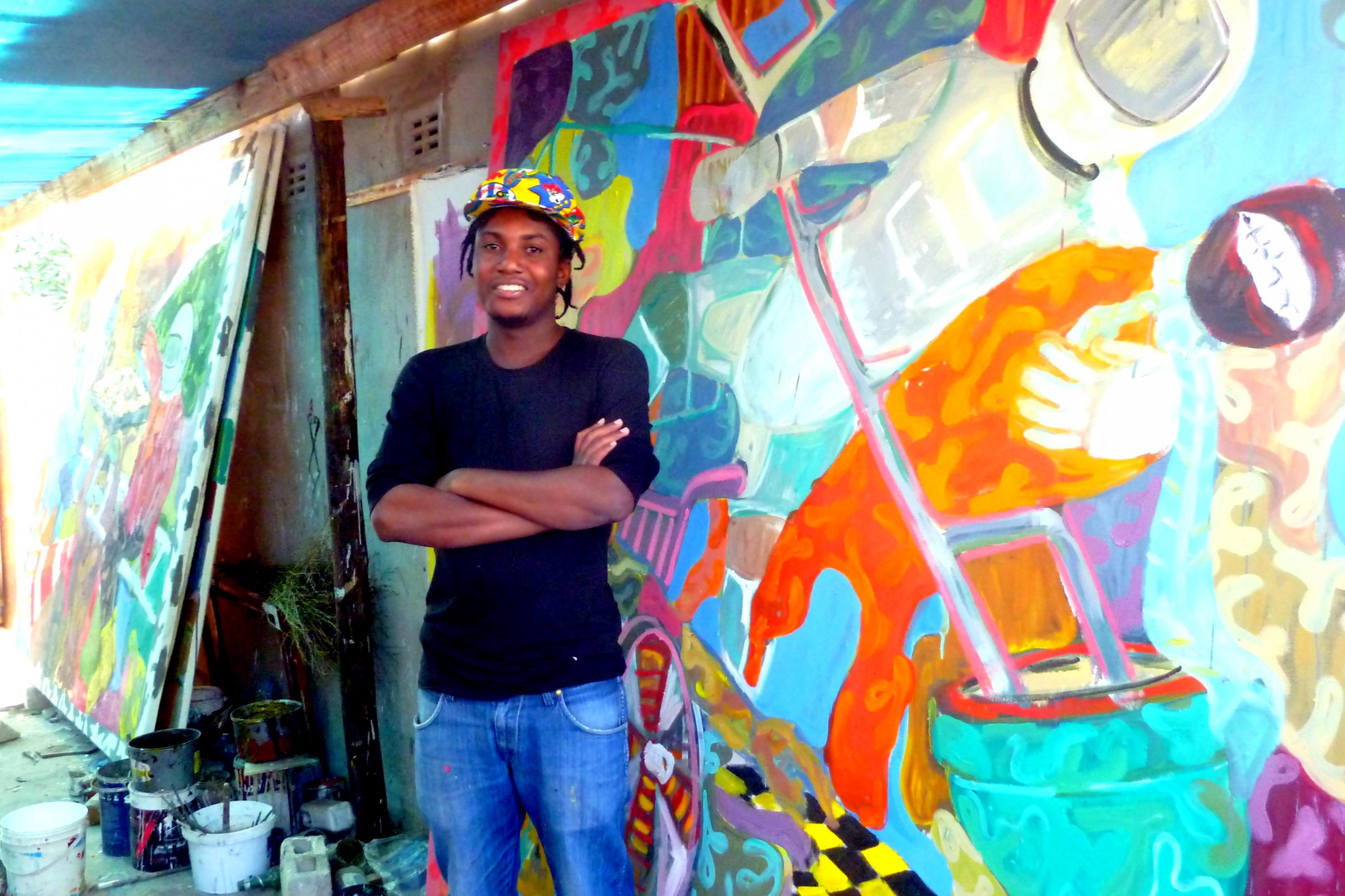 Maler Gresham Nyaude steht in seinem Atelier, seine großformatigen Gemälde lehnen hinter ihm an der Wand