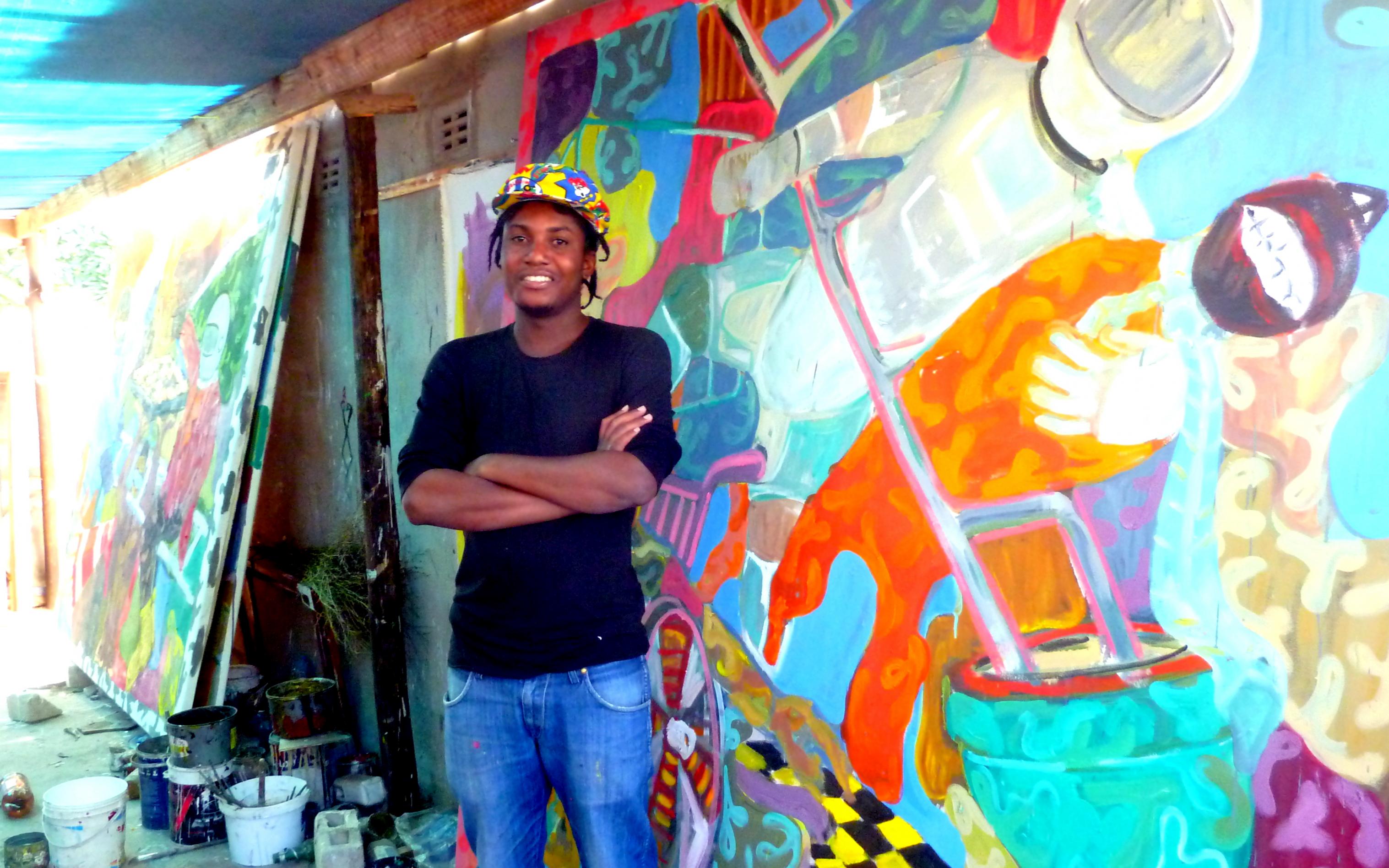 Maler Gresham Nyaude steht in seinem Atelier, seine großformatigen Gemälde lehnen hinter ihm an der Wand