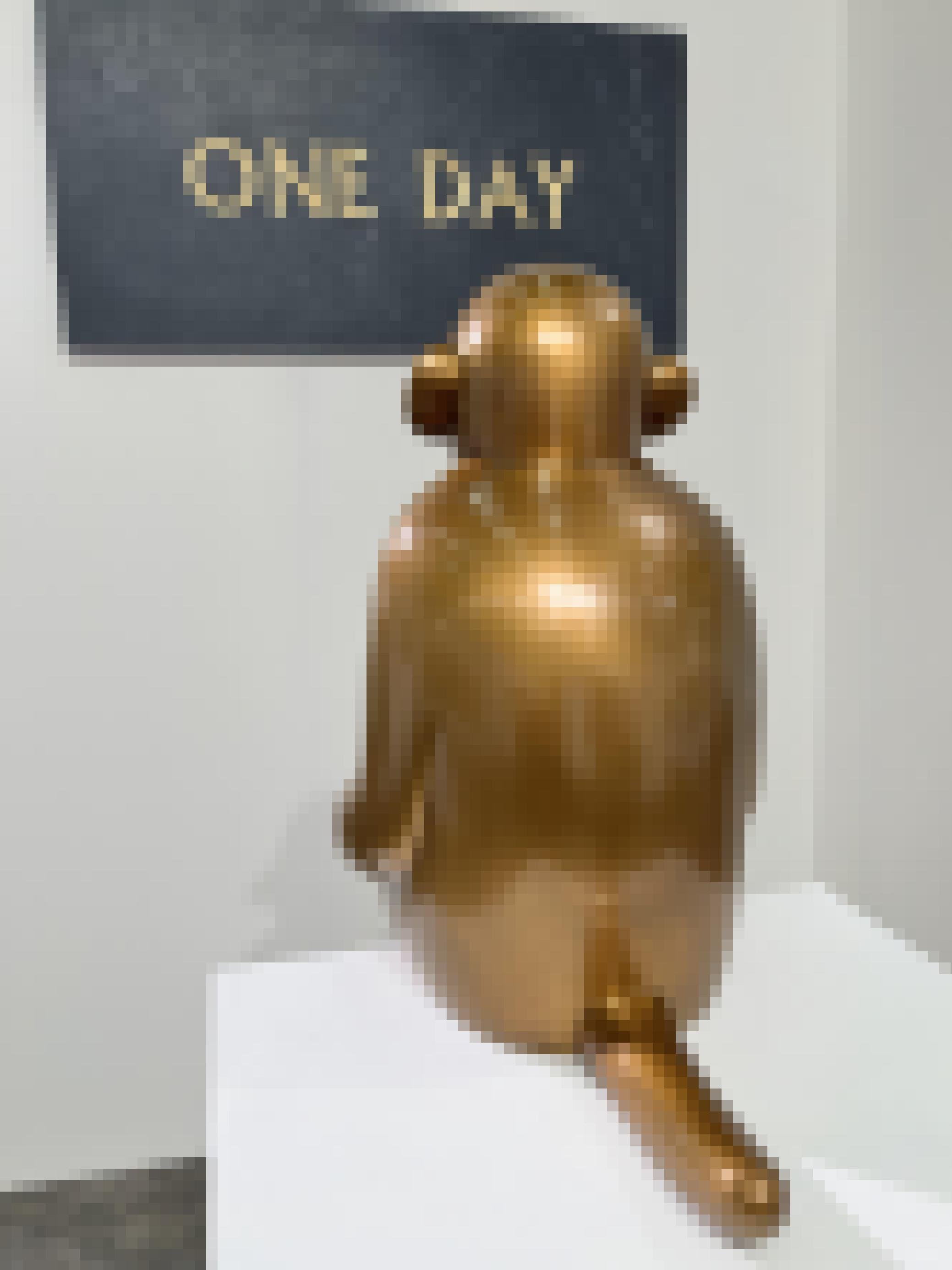 Eine goldene Skulptur eines Affen, der auf  ein Schild „on day“ schaut