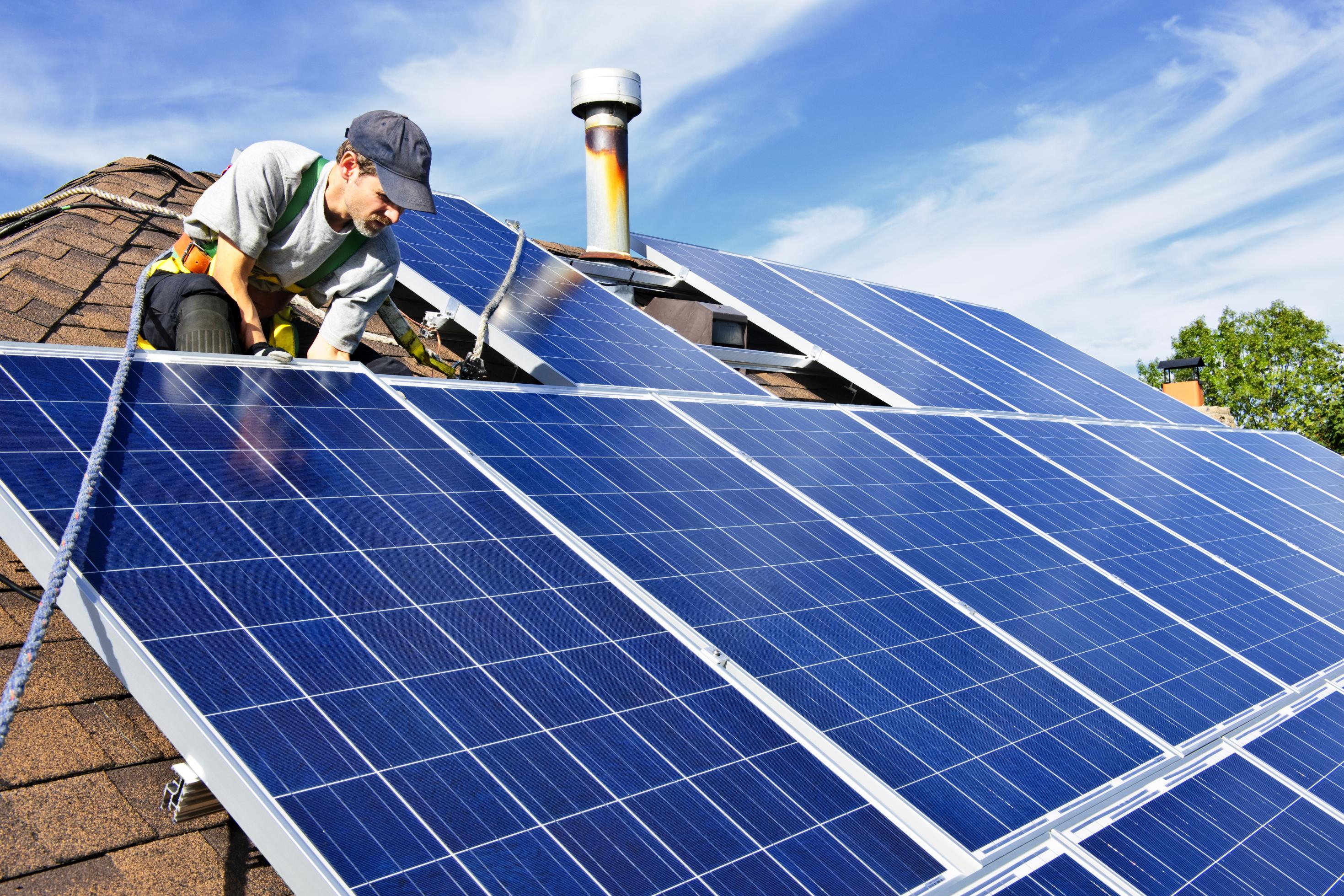 Ein Mann installiert Solarzellen auf einem Dach.