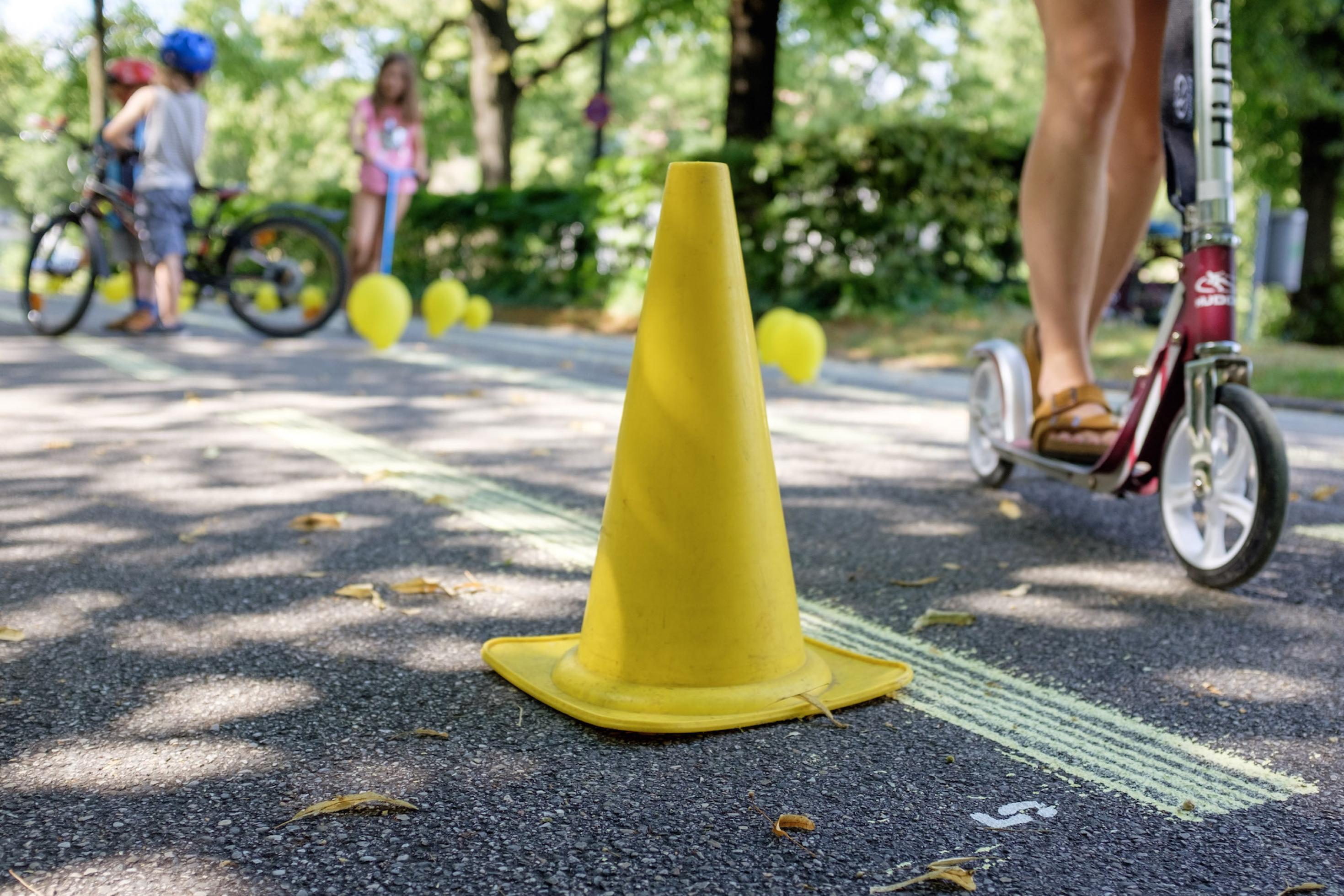 Ein gelber Verkehrshut steht auf der Straße und gelbe Ballons sind auf dem Asphalt befestigt