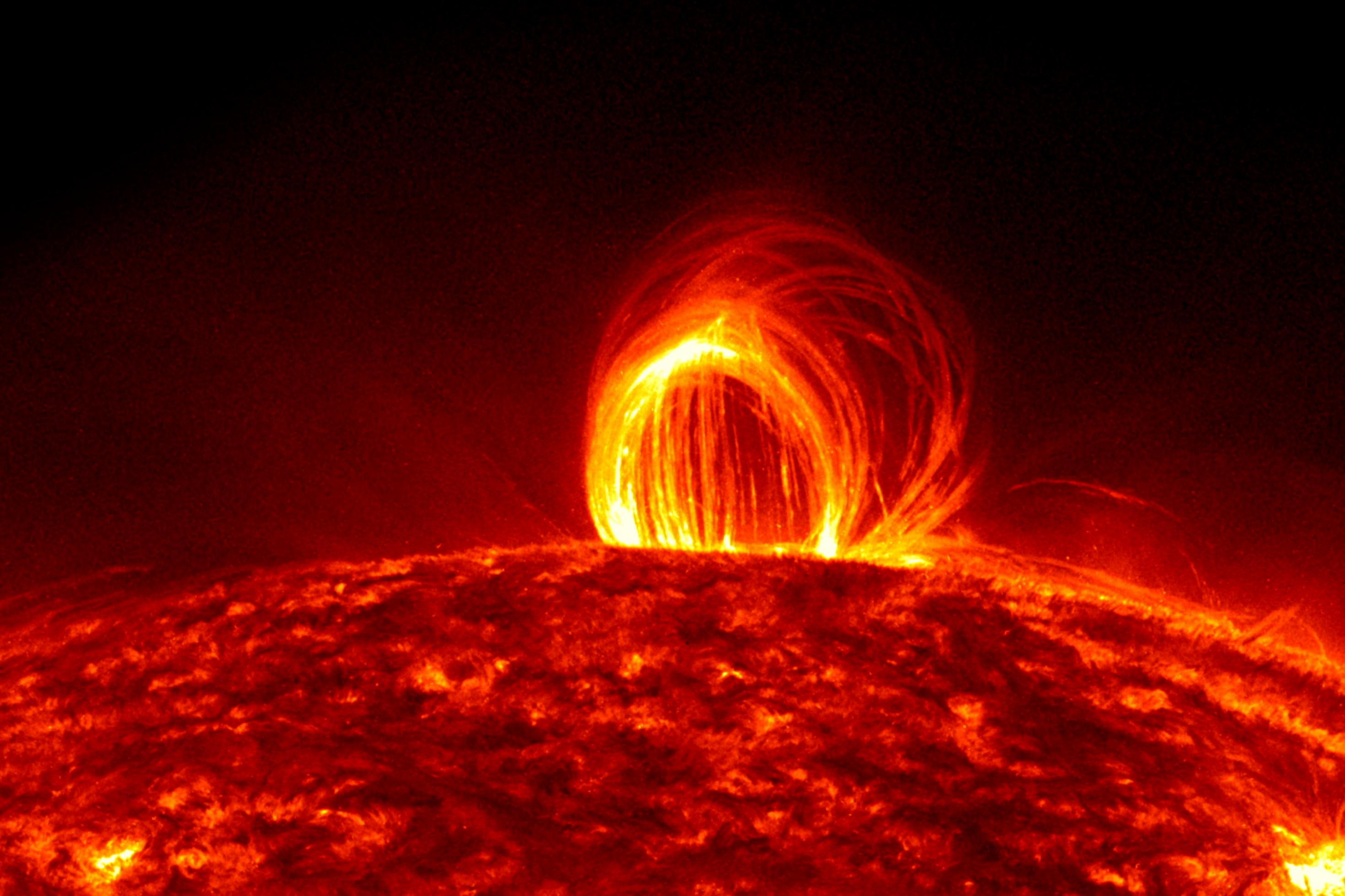 Foto der rot glühenden Oberfläche der Sonne, aus der ein grellgelber Bogen hervorsteht.