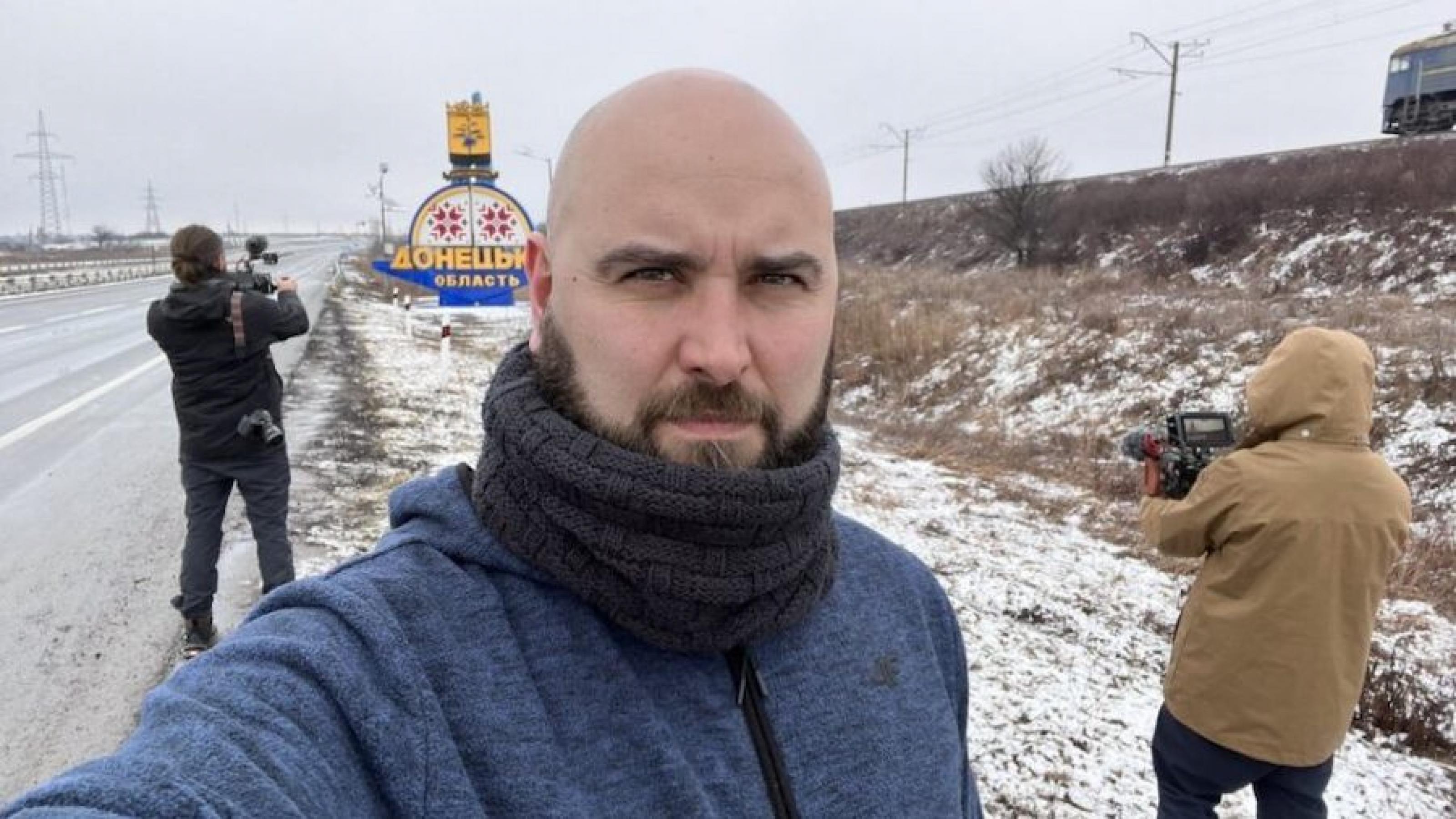 Ein Selfie des Journalisten auf einer verschneiten Straße, im Hintergrund stehen zwei Kameramänner