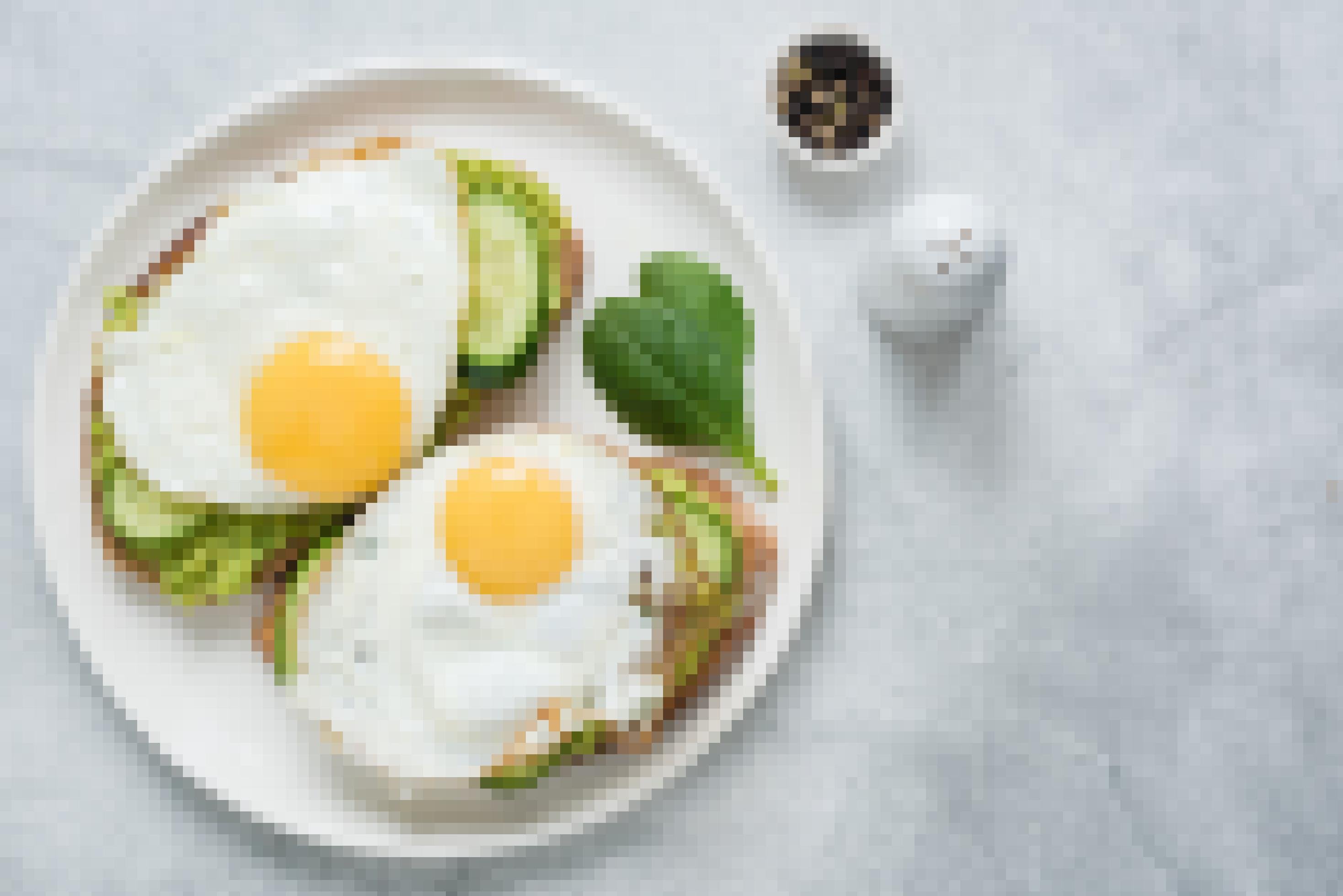 Draufsicht. Zwei Toasts mit Avocado, Gurke und Ei auf weißem Teller vor grauem Betonhintergrund.