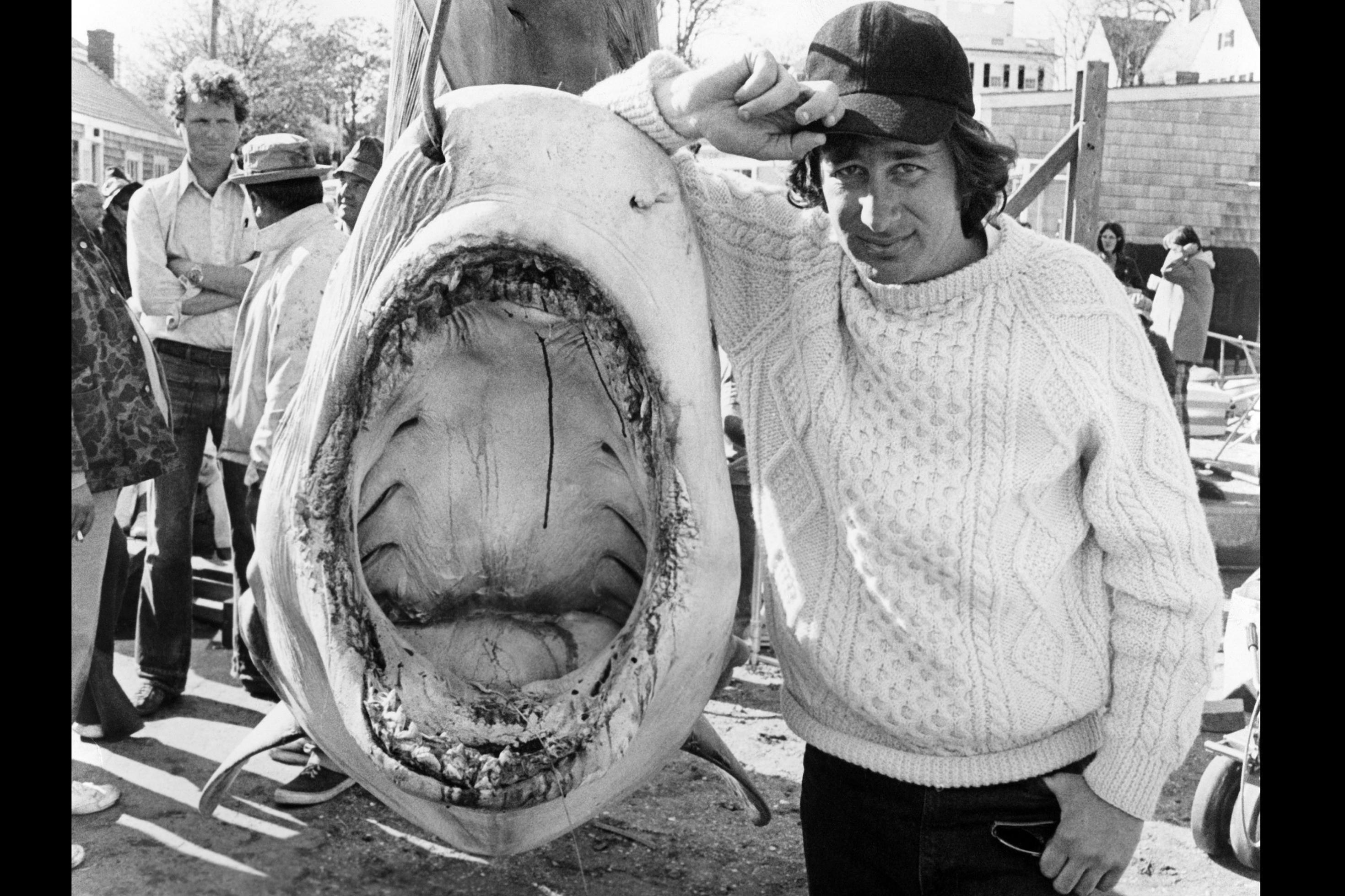 Regisseur Steven Spielberg posiert neben einem Hai an einem Angelhaken.