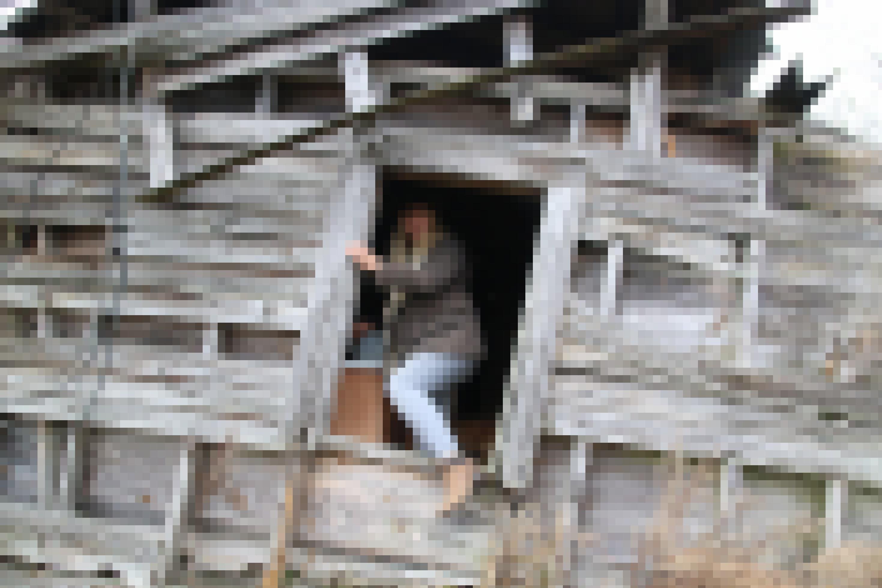 Stacie Marshall klettert durch den Eingang einer verfallenen Holzhütte