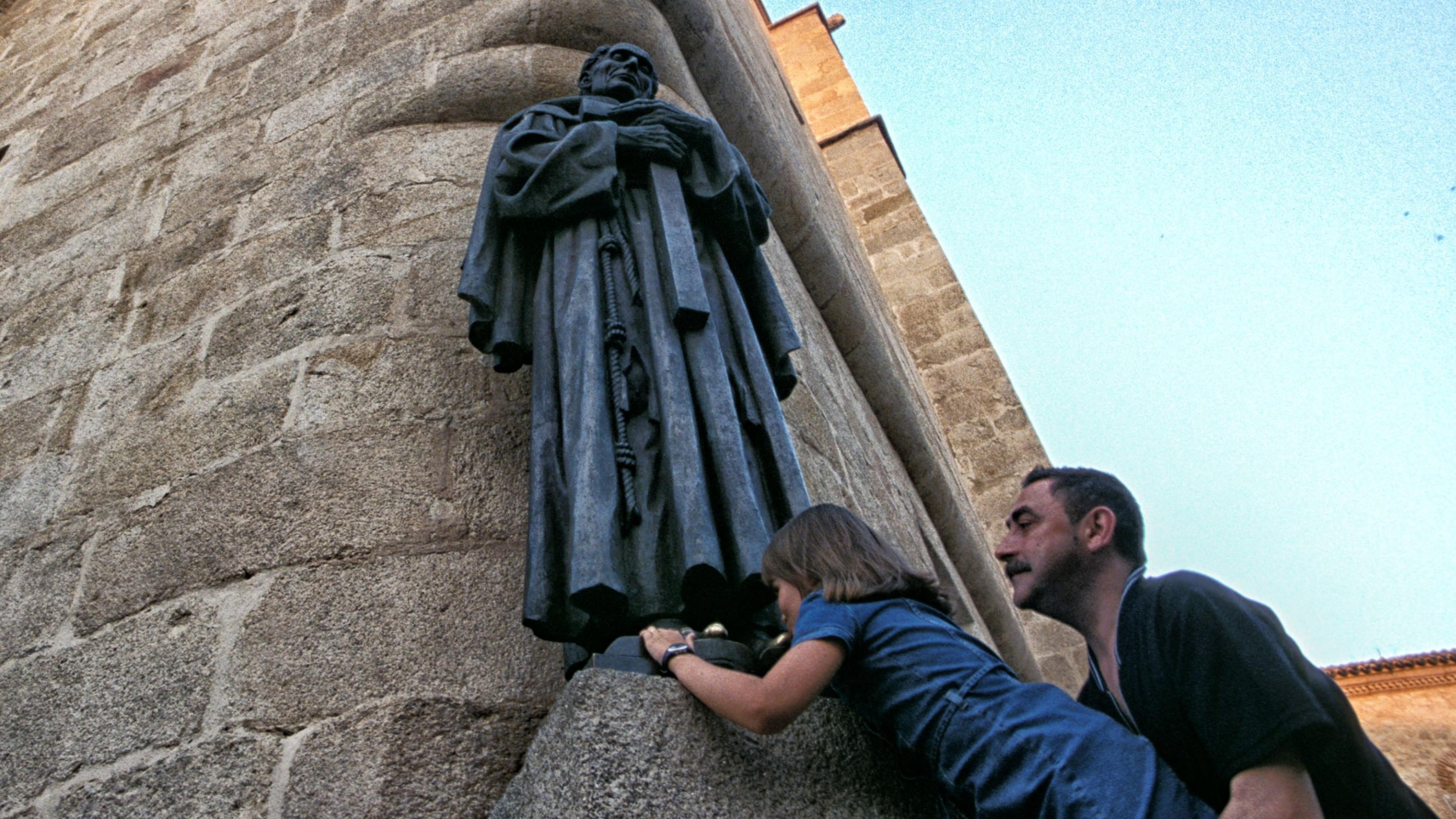 Einer steinernen Statue eines Priesters werden die Füsse geküsst. Eine Tradition im südspanischen Caceres