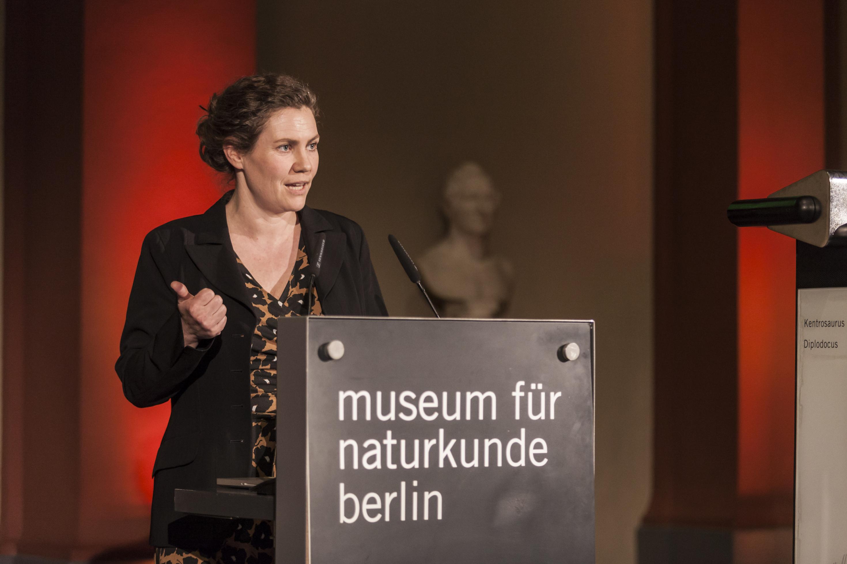Eine Frau am Rednerpult, auf dem „Museum für Naturkunde“ steht.