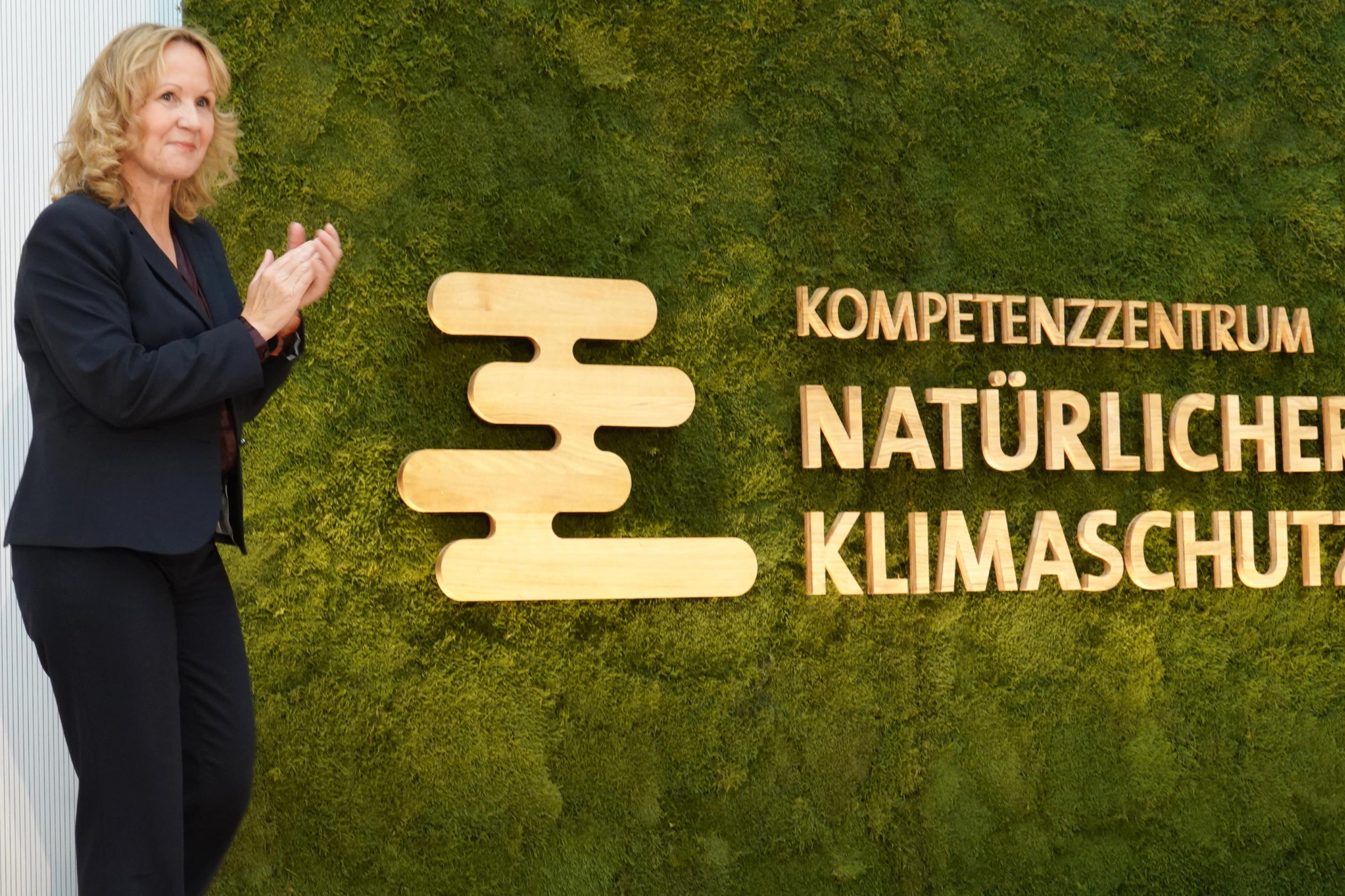 Lemke neben einer grünen Wand mit der Inschrift Natürlicher Klimaschutz