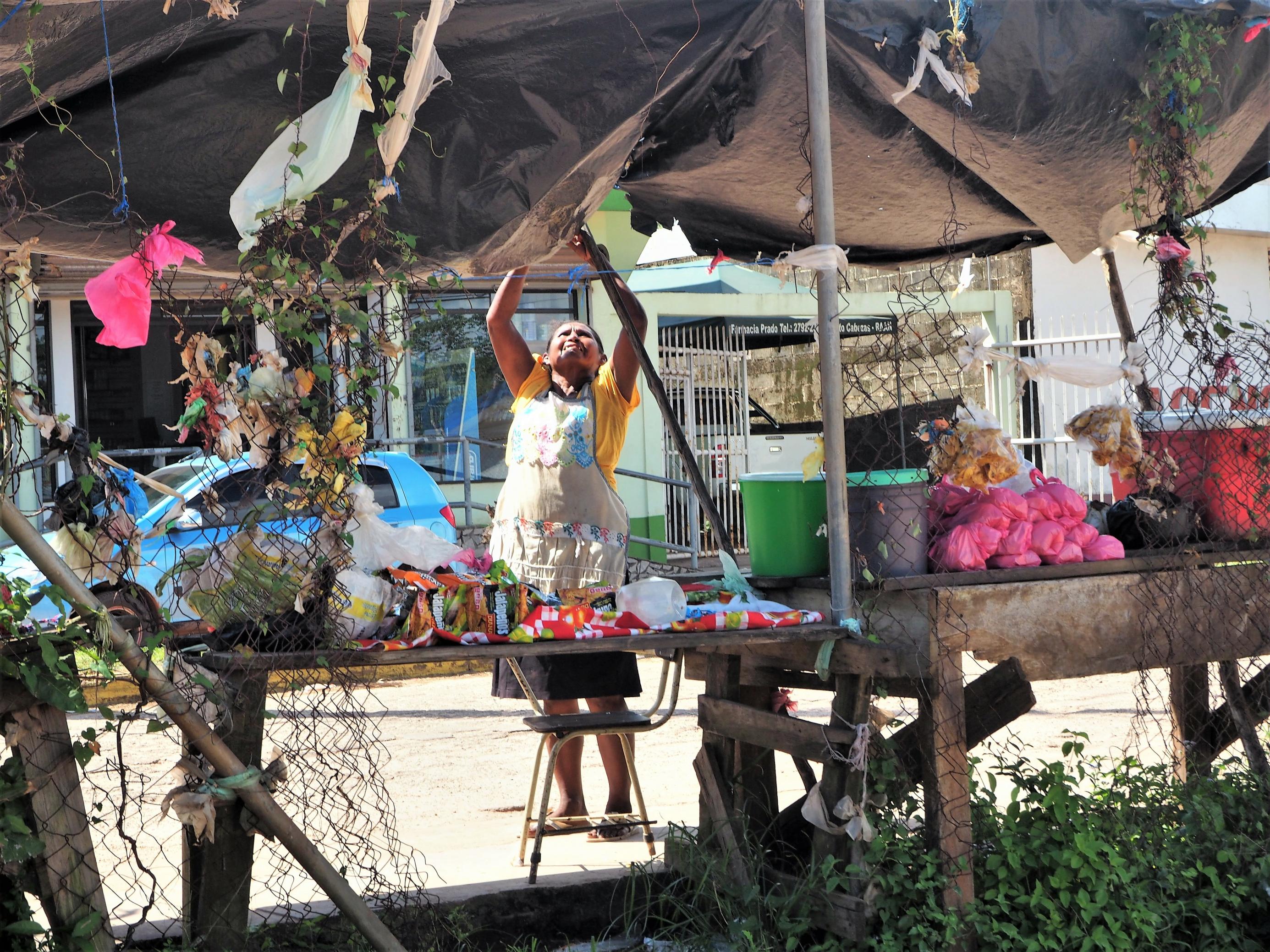 Eine Straßenverkäuferin in Bilwi, Puerto Cabezas, der Hauptstadt der nördlichen Karibikküste zieht eine zerschlissene Plastikplane über ihre Waren.