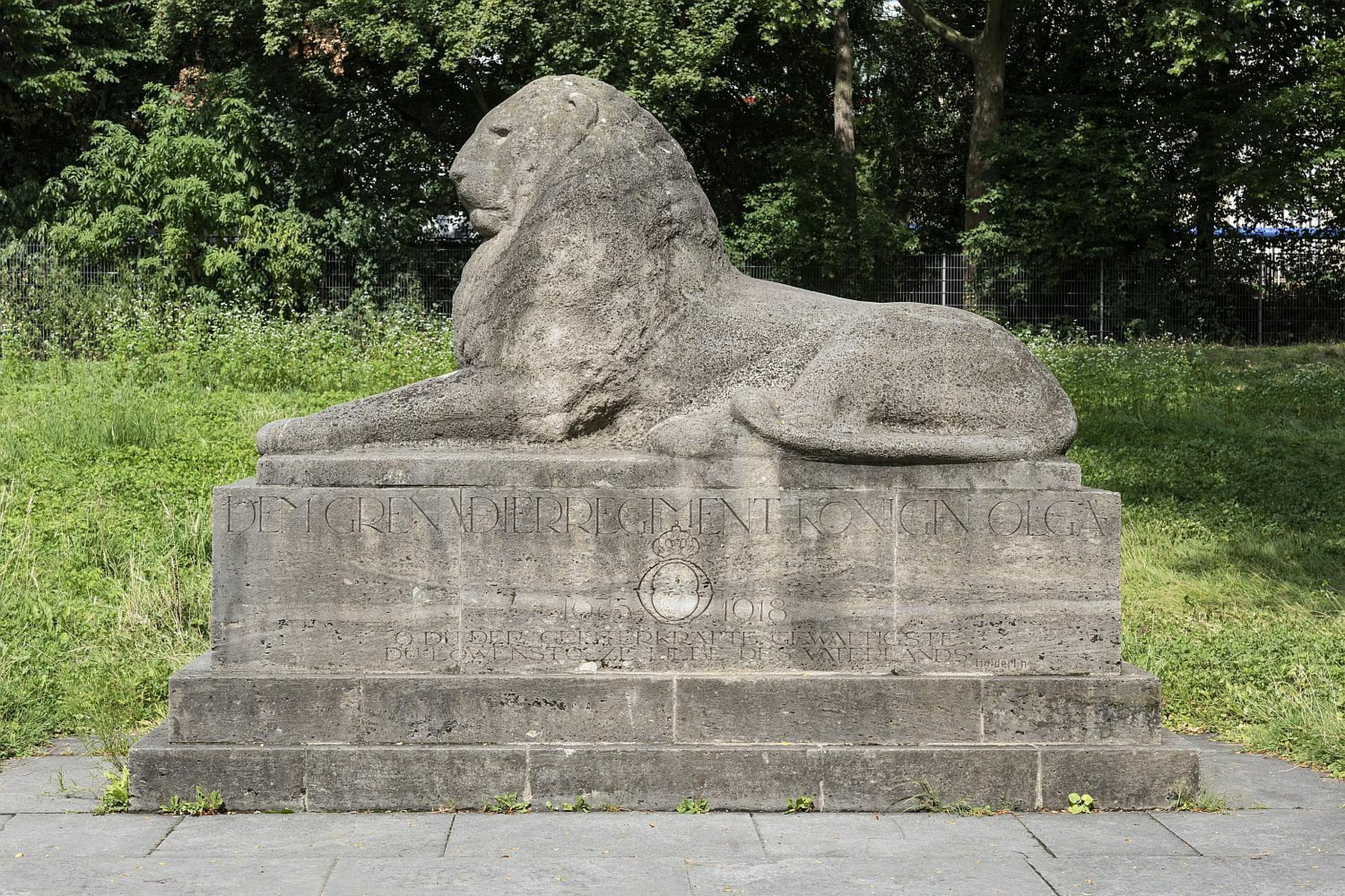 Skulptur eines liegenden, männlichen Löwen. Die Inschrift auf dem Sockel erinnert an das Grenadier-Regiment Königin Olga.