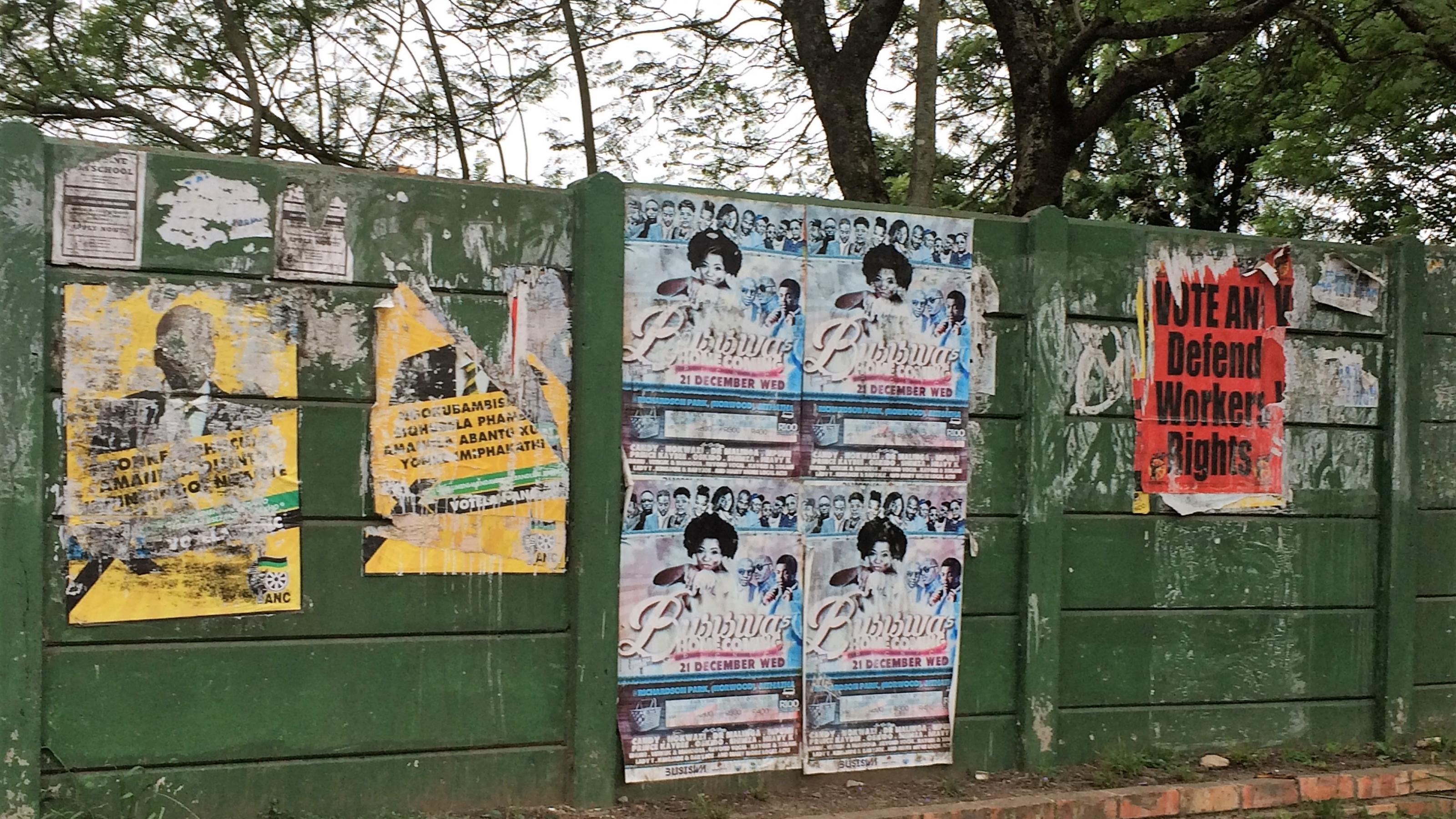 An einer Mauer hängen verwitterte Wahlplakate von vorherigen Abstimmungen.