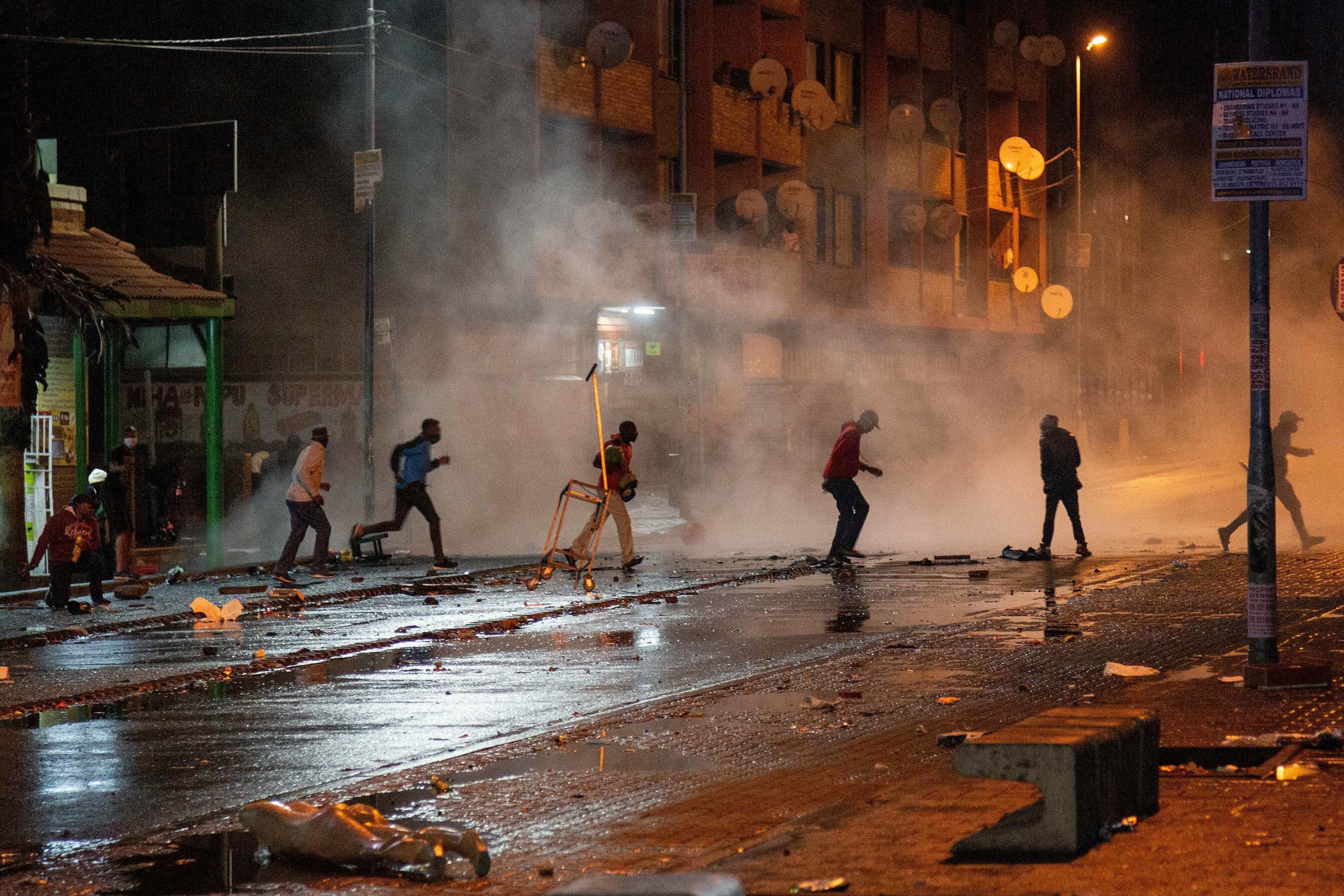 Es ist dunkel, rennende Männer während der Ausschreitungen auf der Straße zu sehen, die Polizei setzt Tränengas ein.