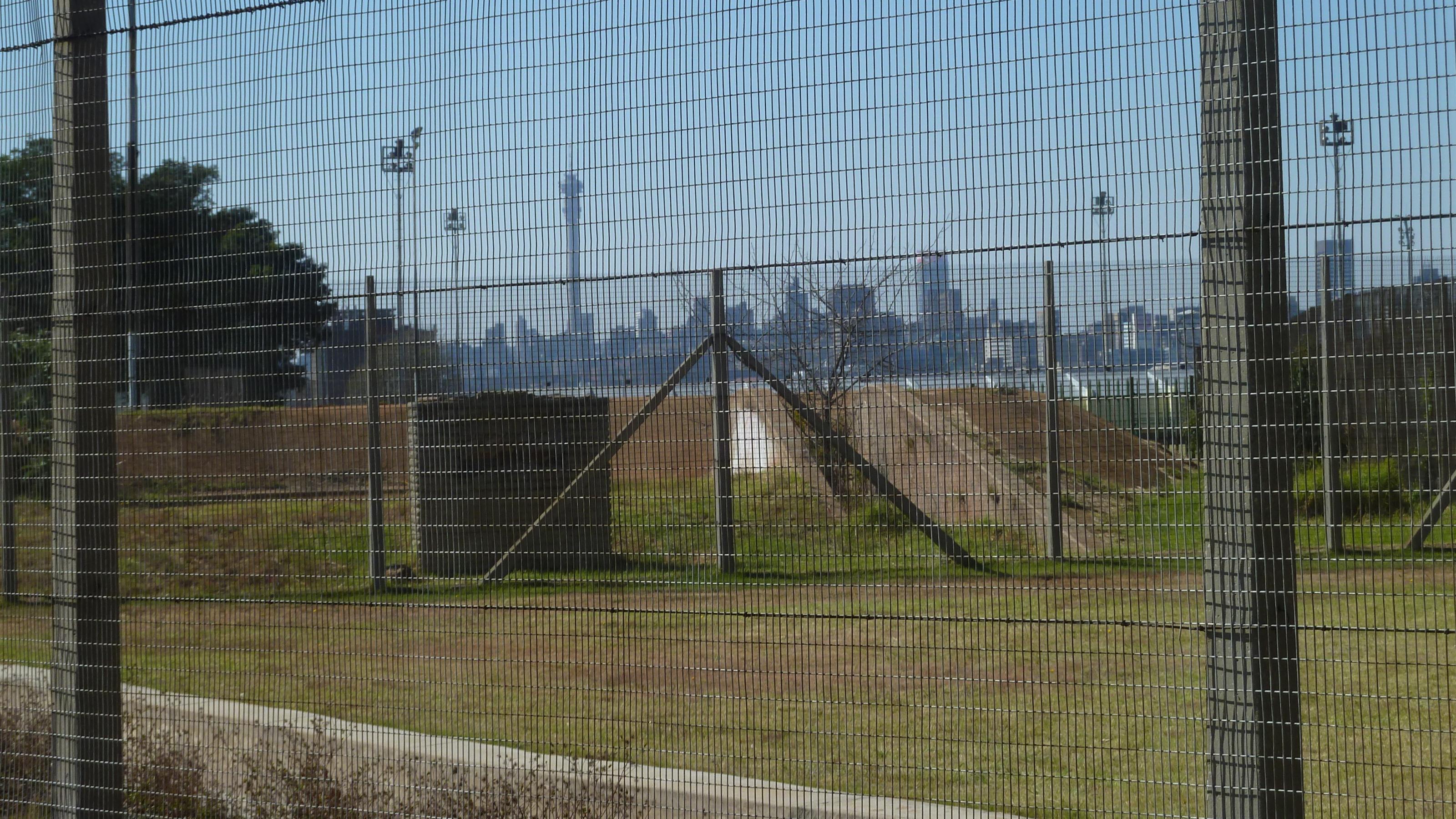Blick durch einen Gitternzaun auf die Skyline von Johannesburg