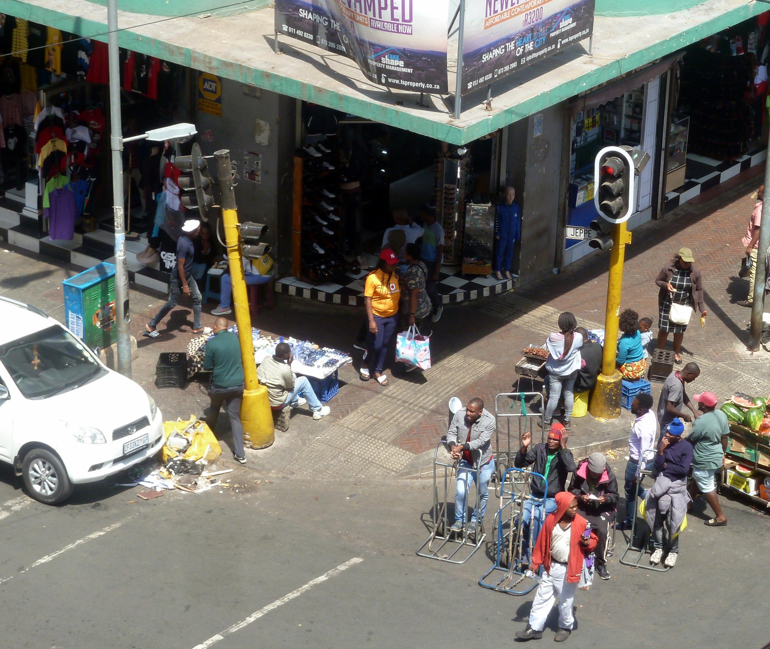 Ein Blick auf eine Straßenkreuzung im Zentrum Johannesburgs, Geschäfte, Händler, Passanten
