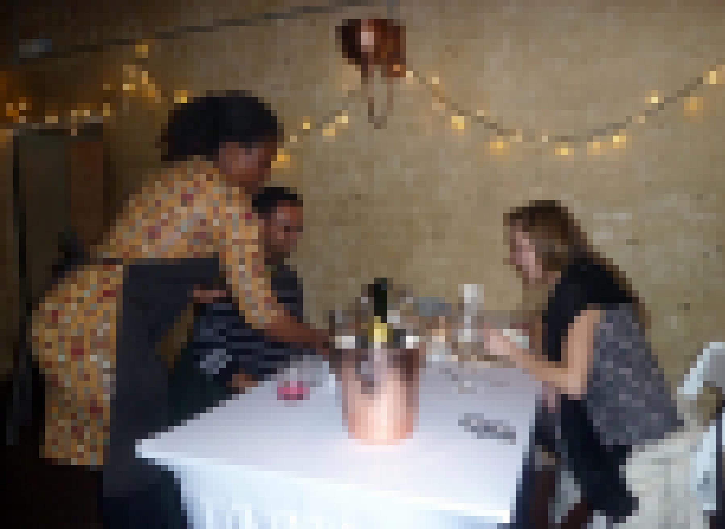 Die Kellnerin serviert dem Paar Crous und Sarawan gerade den nächsten Gang, auf dem Tisch steht eine Sektflasche im Kühler.