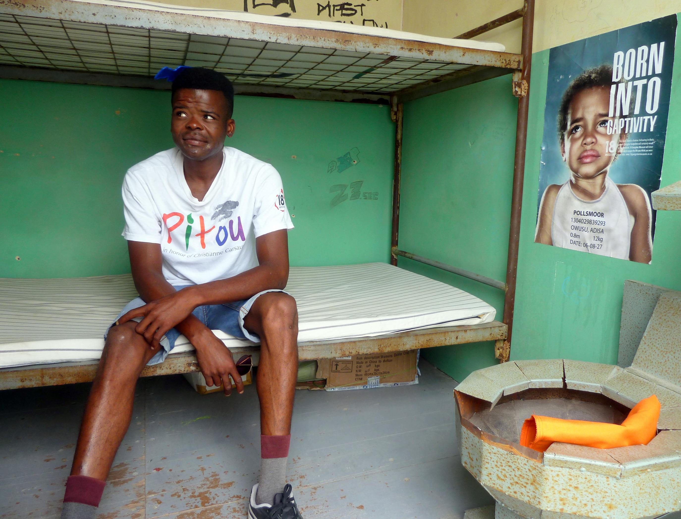 Samkelwe Vuza sitzt auf dem Bett des Gefängniszellen-Nachbaus im  Museum