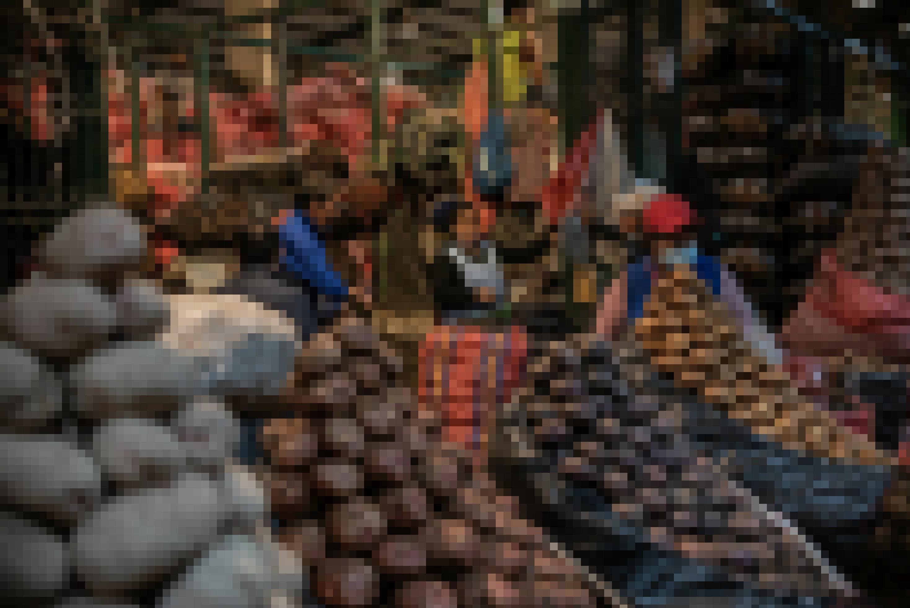 Eine Markthalle des Nachts, schummriges Licht. Im Vordergrund nach Sorten aufgestapelte Kartoffeln, dahinter Marktfrauen und noch meterhohe Stapel mit gefüllten Kartoffelsäcken.