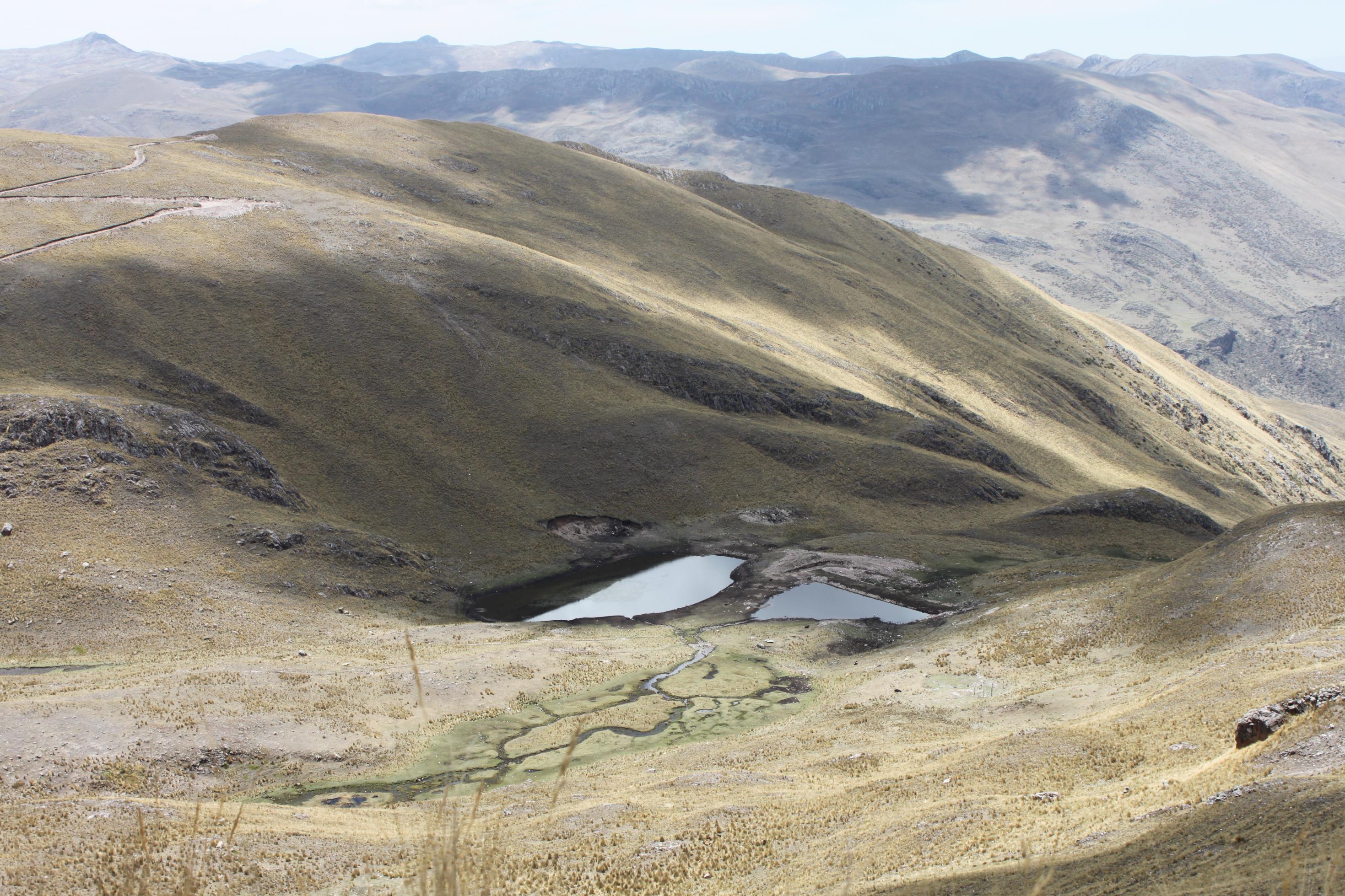 Öde Berglandschaft, verdorrtes Gras, darin zwei kleine Lagunen.