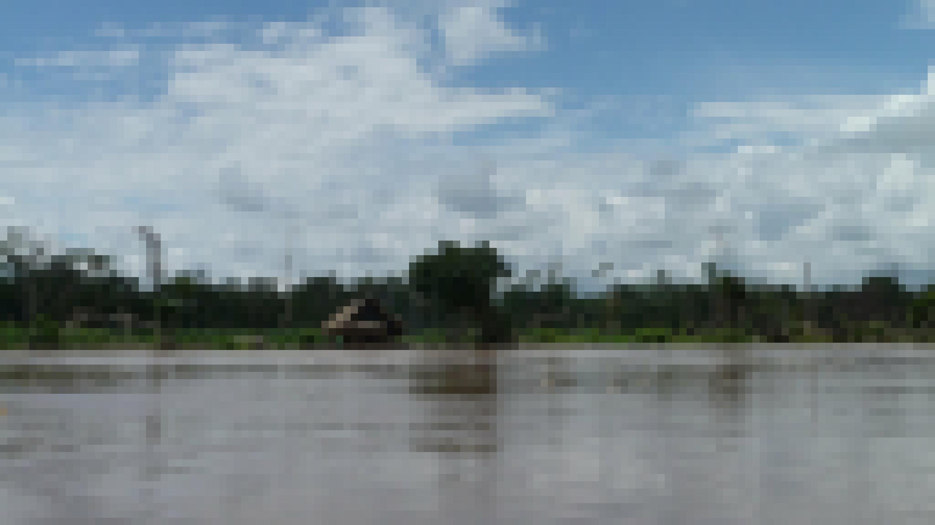 Der Paranapura-Fluss bei Hochwasser. Am Ufer sieht man ein palmstrohbedecktes Holzhaus und über der grünen Wand des tropischen Regenwaldes türmen sich Regenwolken.