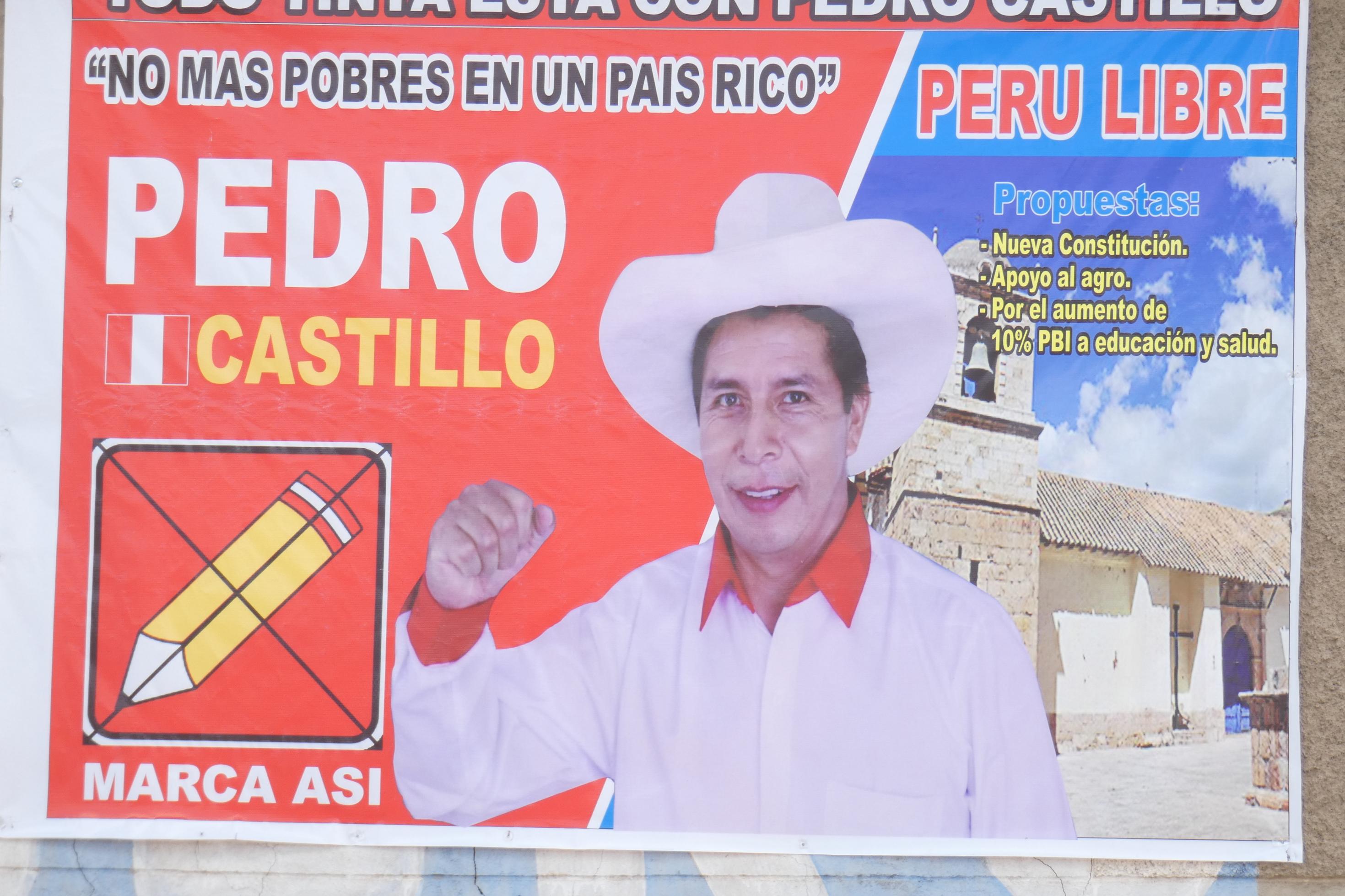 Mann mit Strohhut auf einem Plakat mit rotem Hintergrund. Darauf mehrere Wahlsprüche in spanisch.