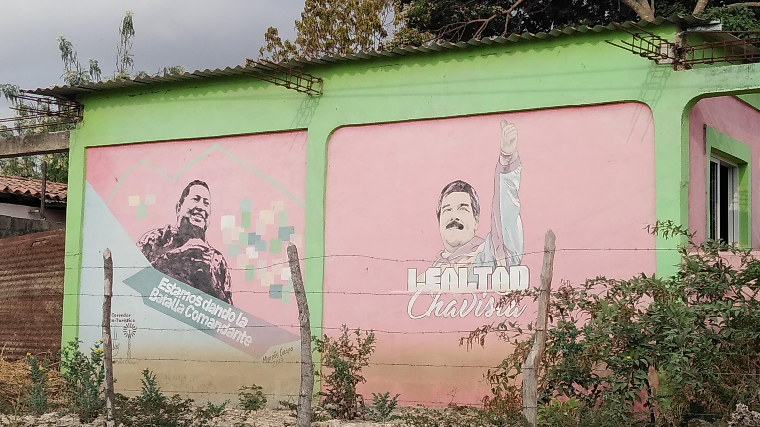 Hellgrüne Häuserwand, auf der zwei gemalte Figuren zu erkennen sind: links der verstorbene venezolanische Präsident Hugo Chavez, rechts der jetzige Präsident Nicolas Maduro.