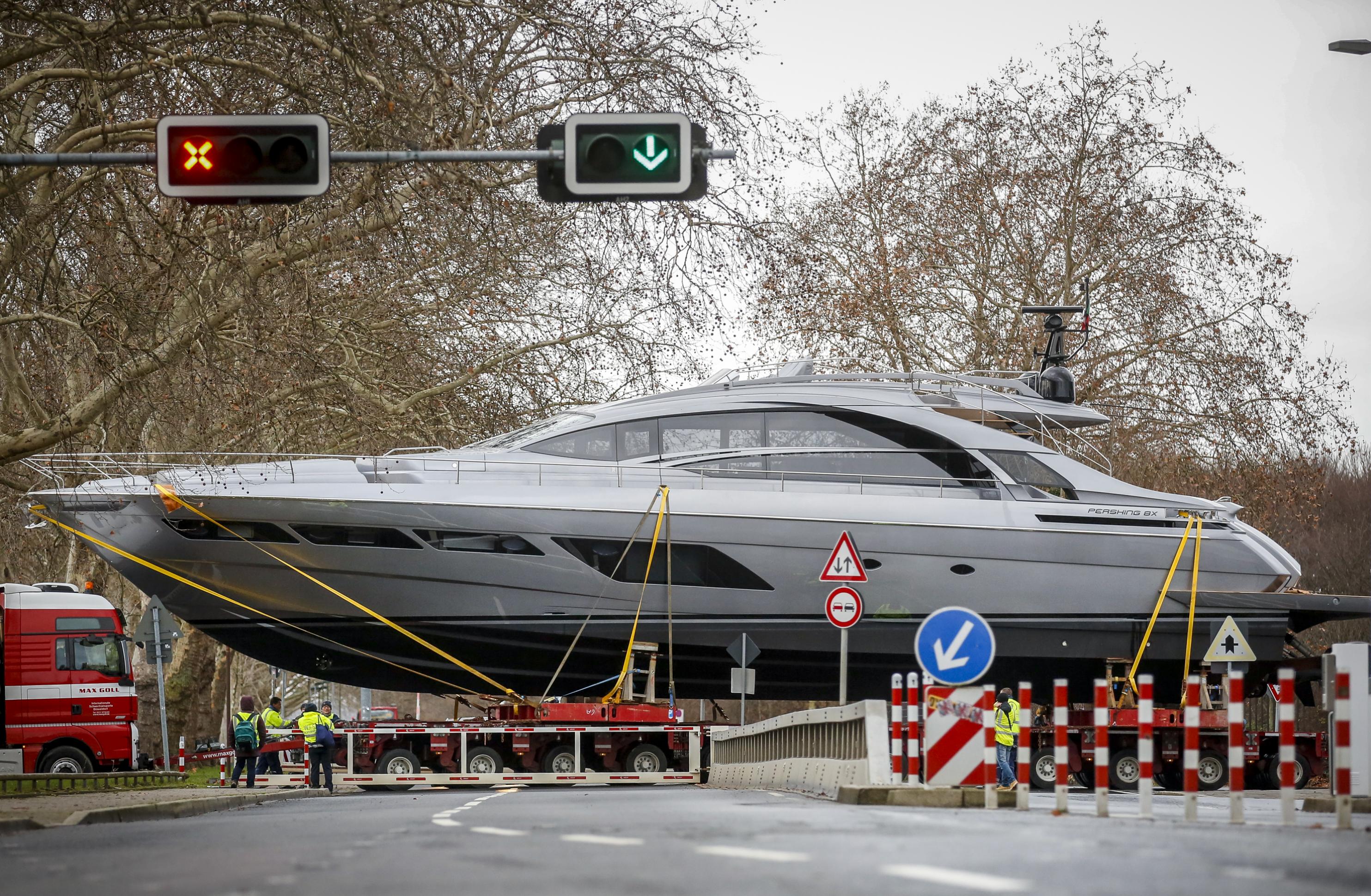 Eine riesige graue Motoryacht wird auf einem Anhänger über eine Kreuzung gezogen.