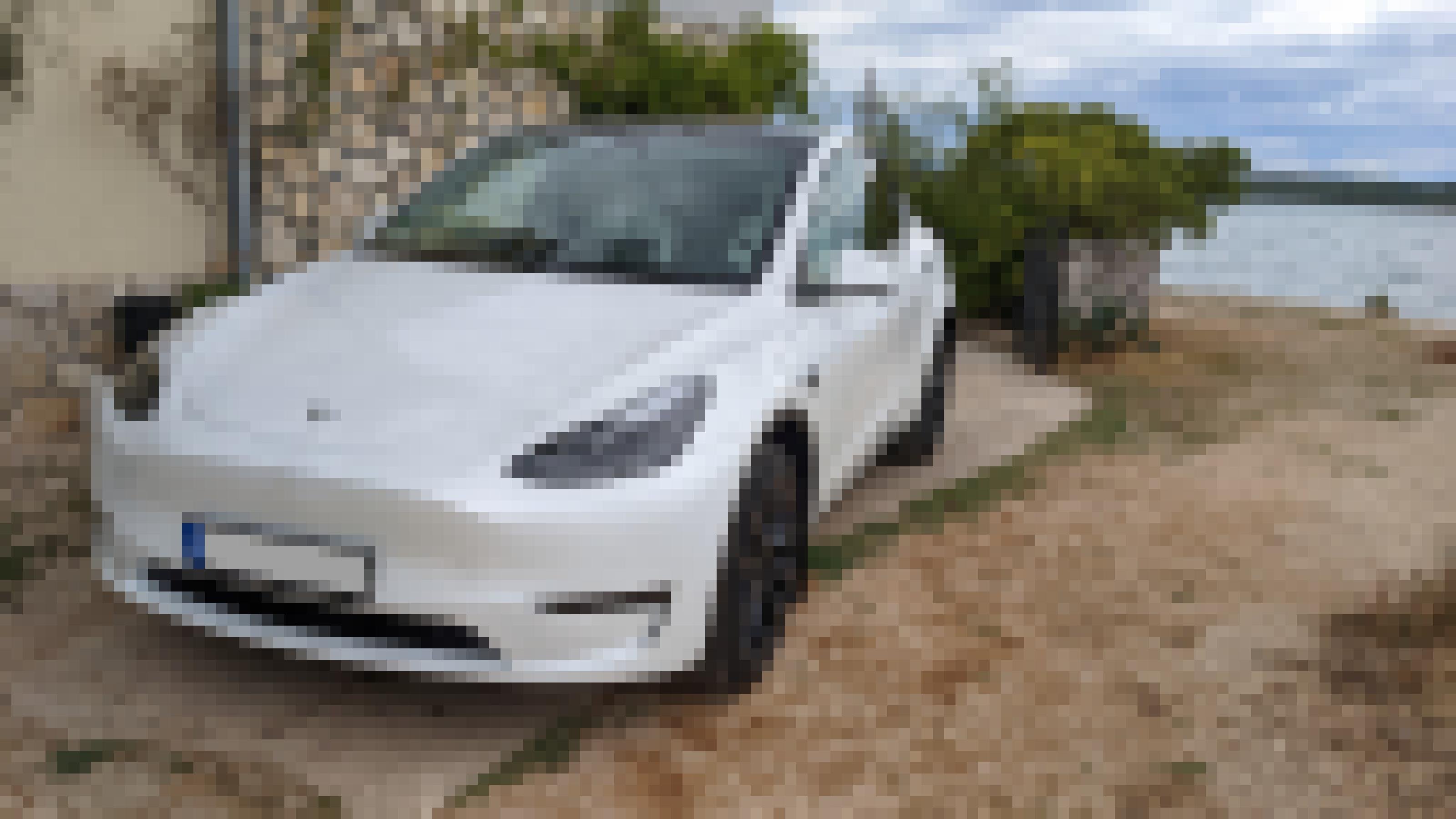 Ein Tesla steht vor einem Ferienhaus, im Hintergrund ist das Meer zu sehen