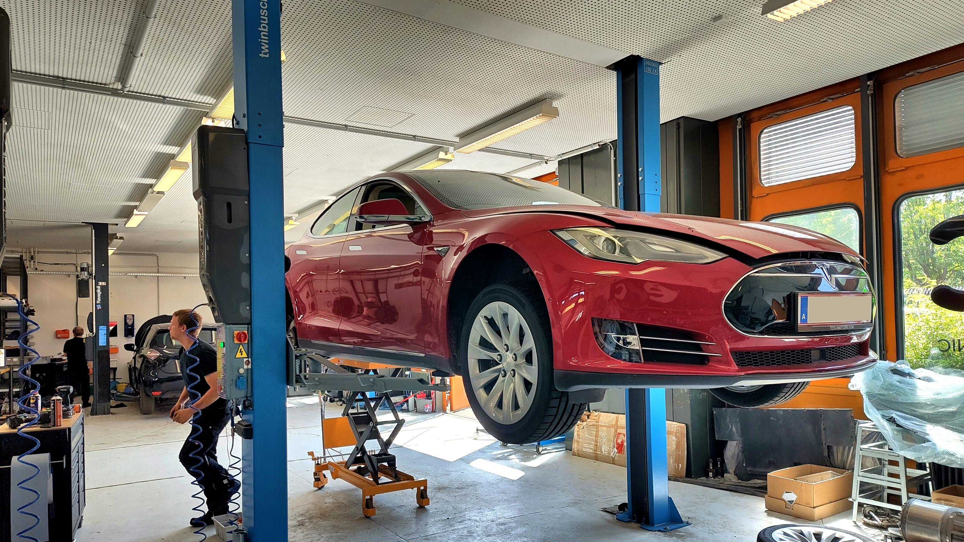 Ein Tesla Model S steht in einer Werkstatt auf einer Hebebühne.