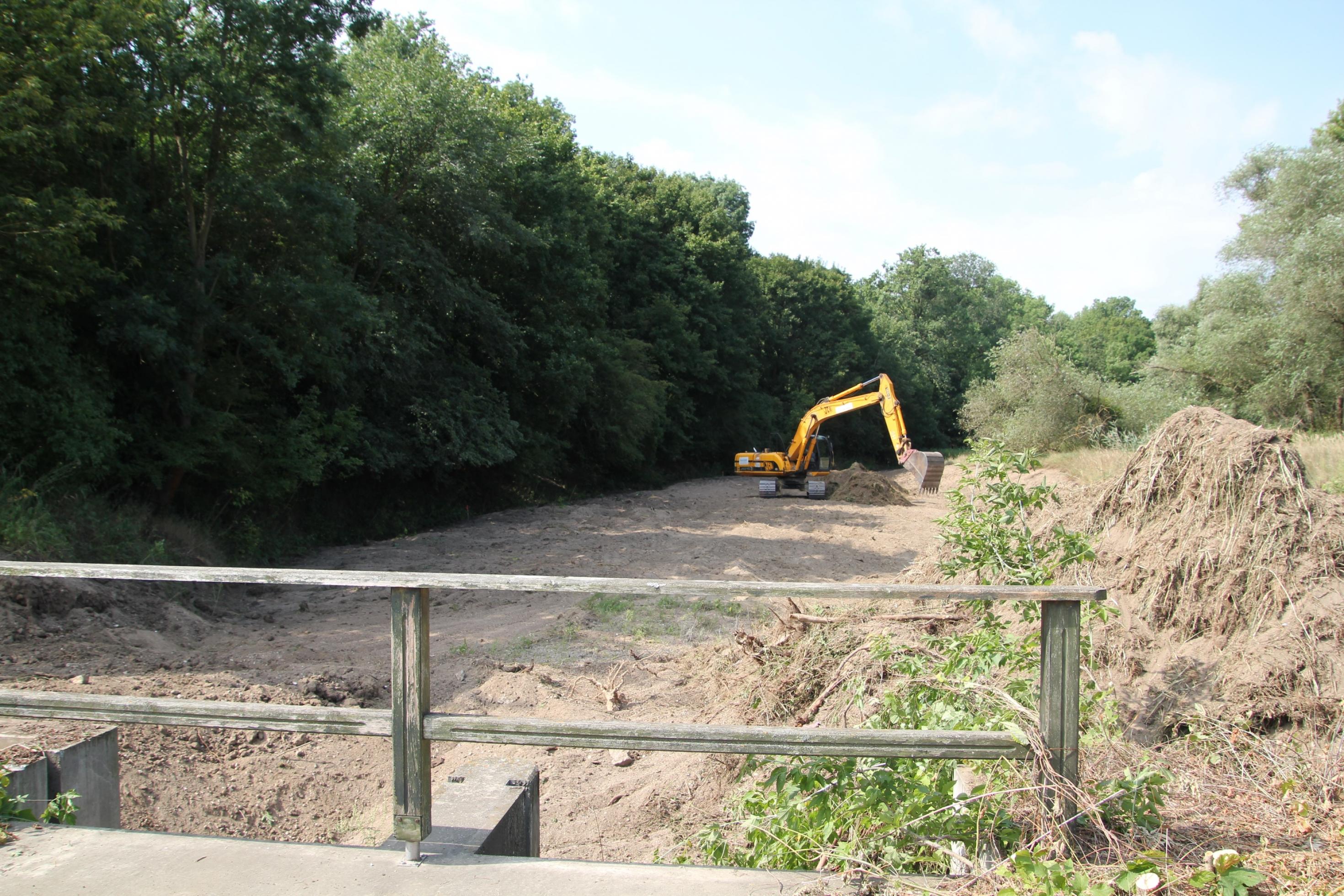 Bagger steht in trockenem Flussbett.