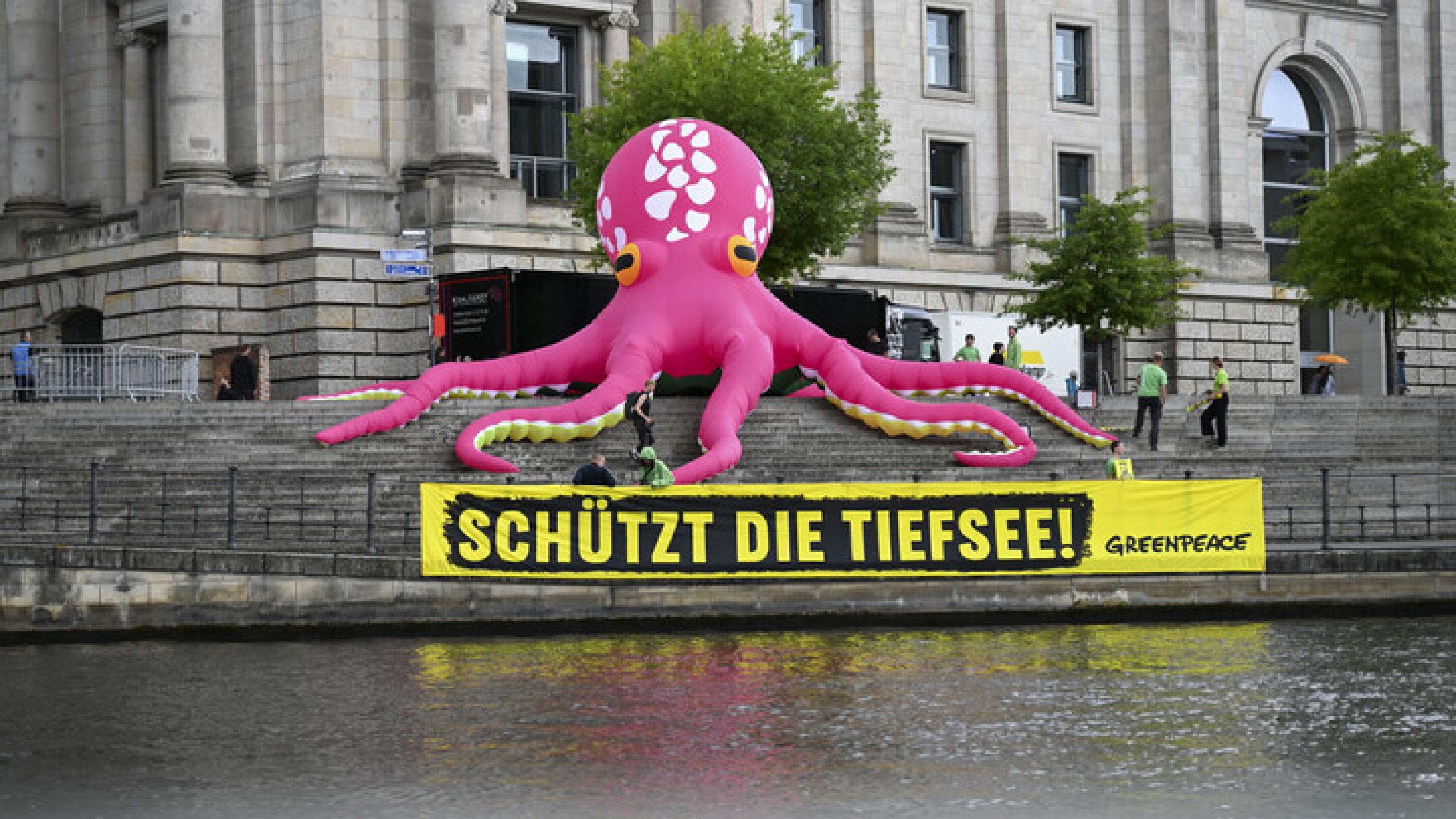 Ein pinker tintenfisch, aufblasbar, den greenpeace aufgestellt hat, darunter ein gelber Banner „schützt die Tiefsee“